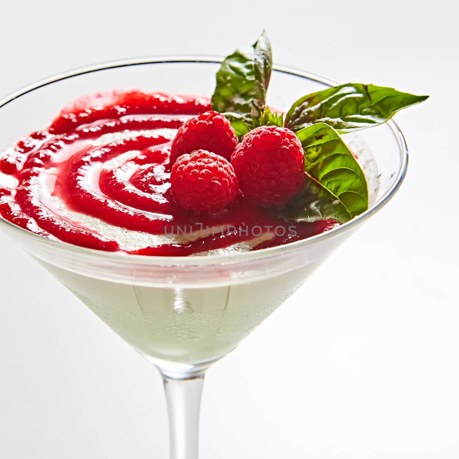 Delicious Italian dessert Panna Cotta with raspberry in small transparent glass.
