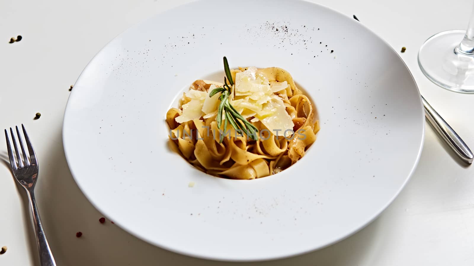 Close-up italian pasta plate with grated parmesan cheese and basil leaf.