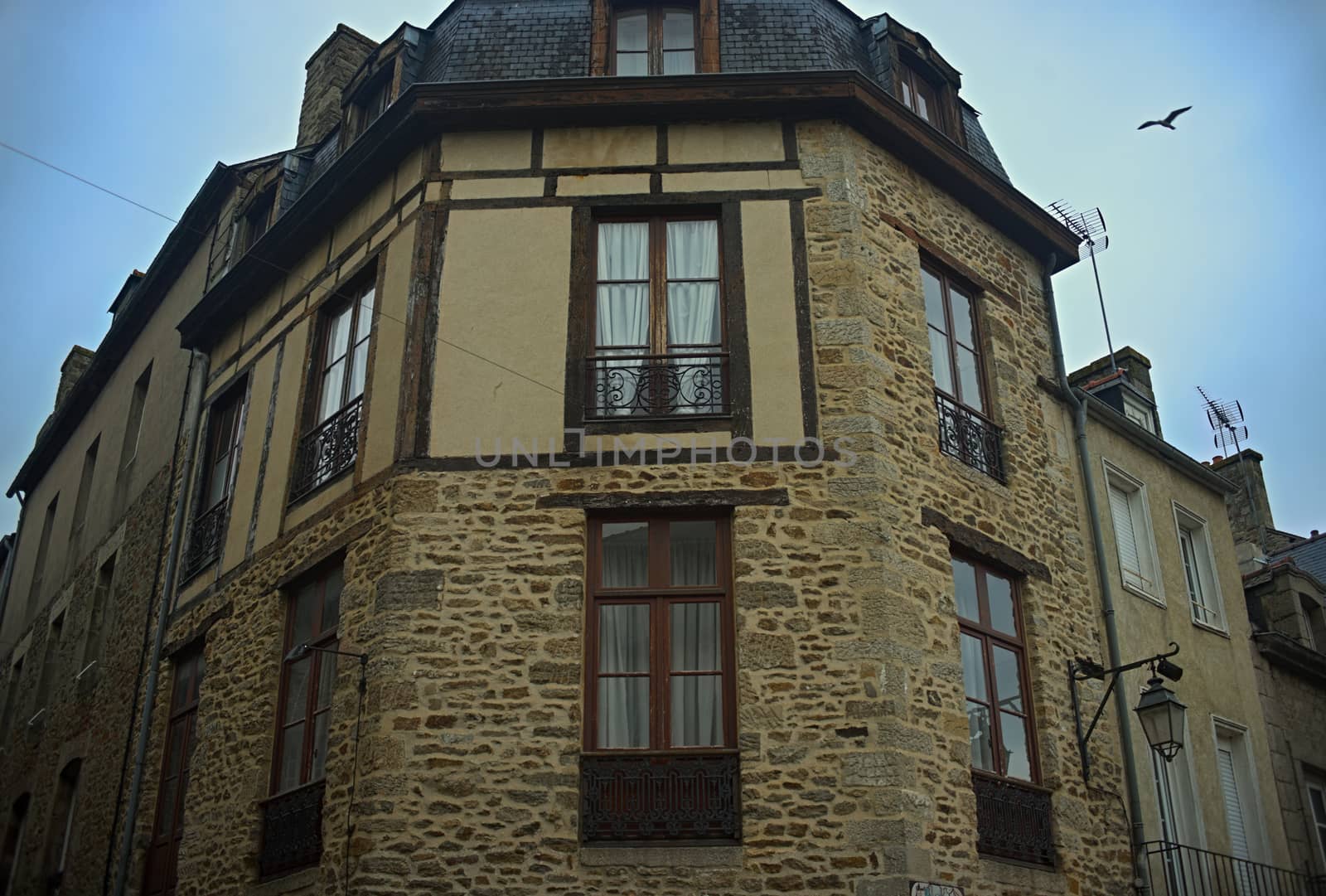 Old traditional French stone corner building with wooden windows