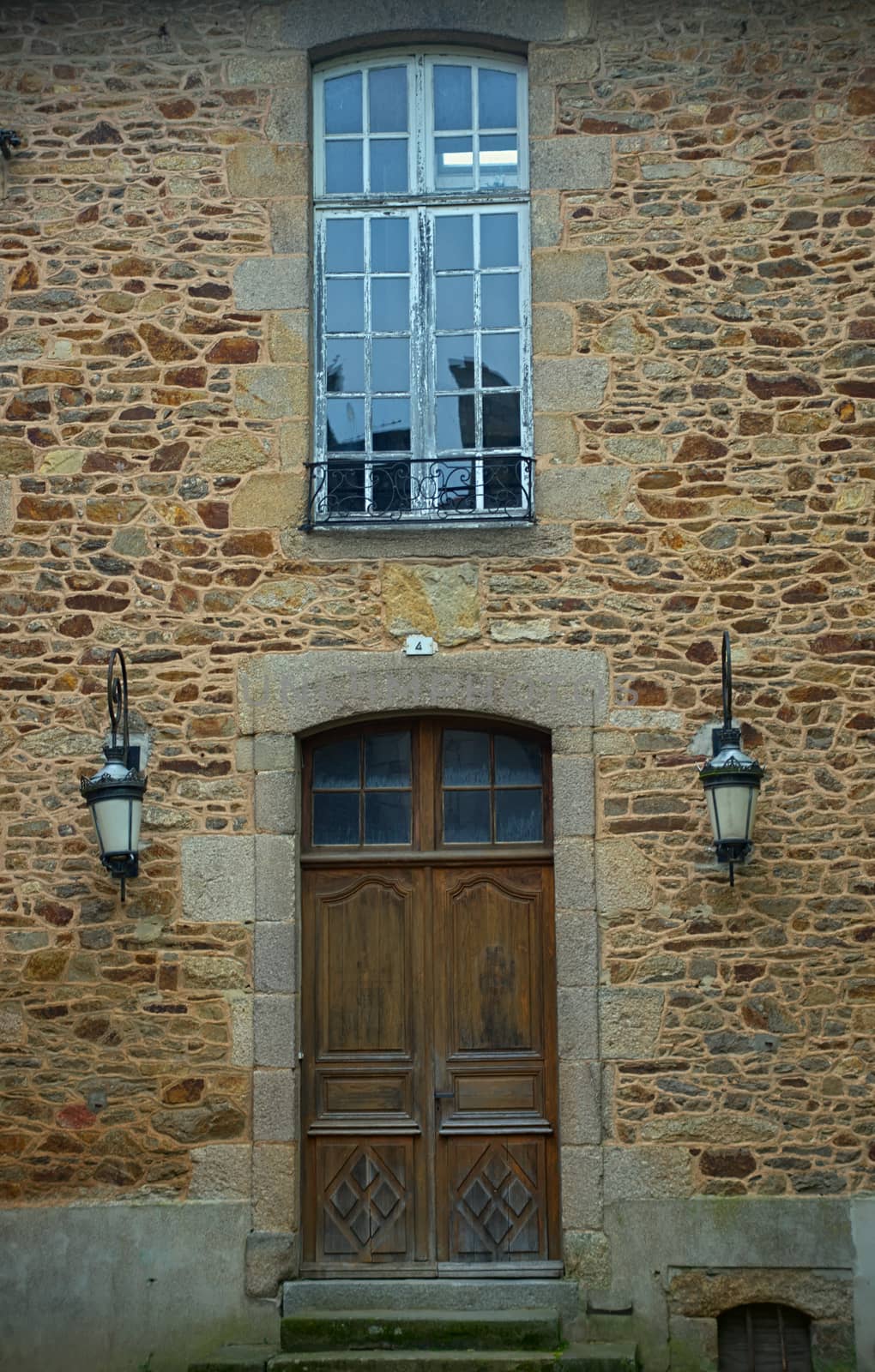 Wooden entrance door and window above on old stone house