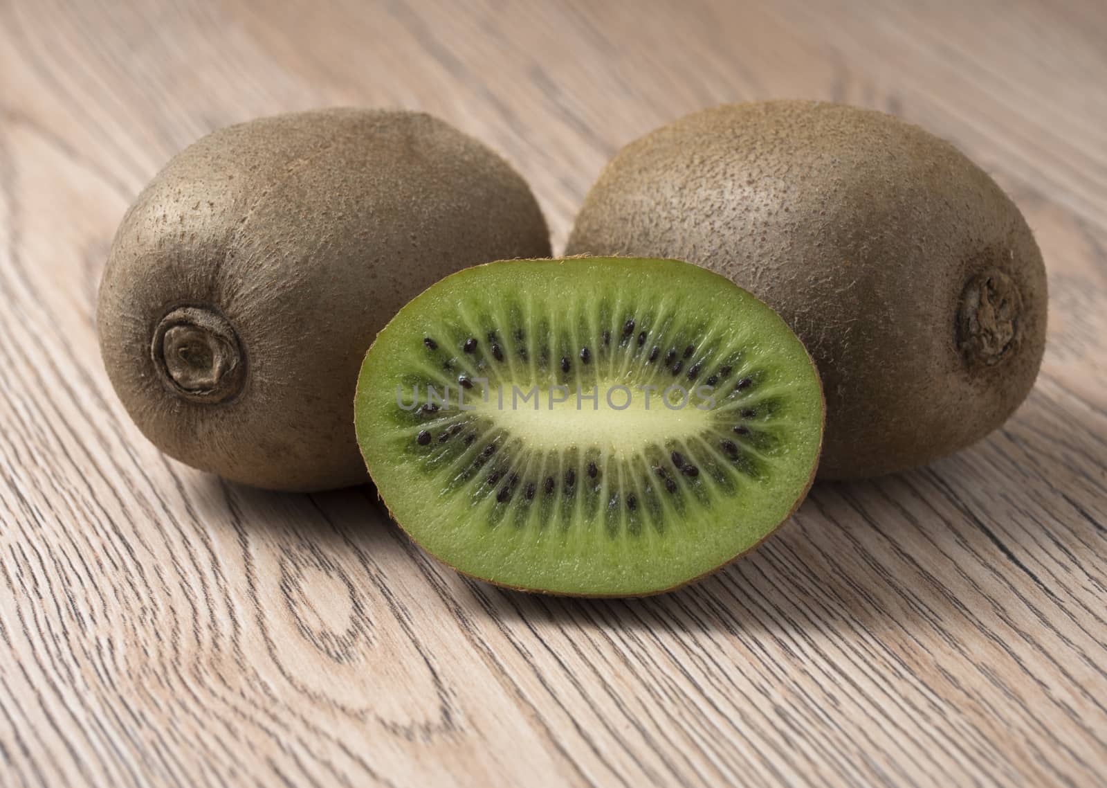 Ripe juicy kiwi fruit with sliced segments on wooden background.