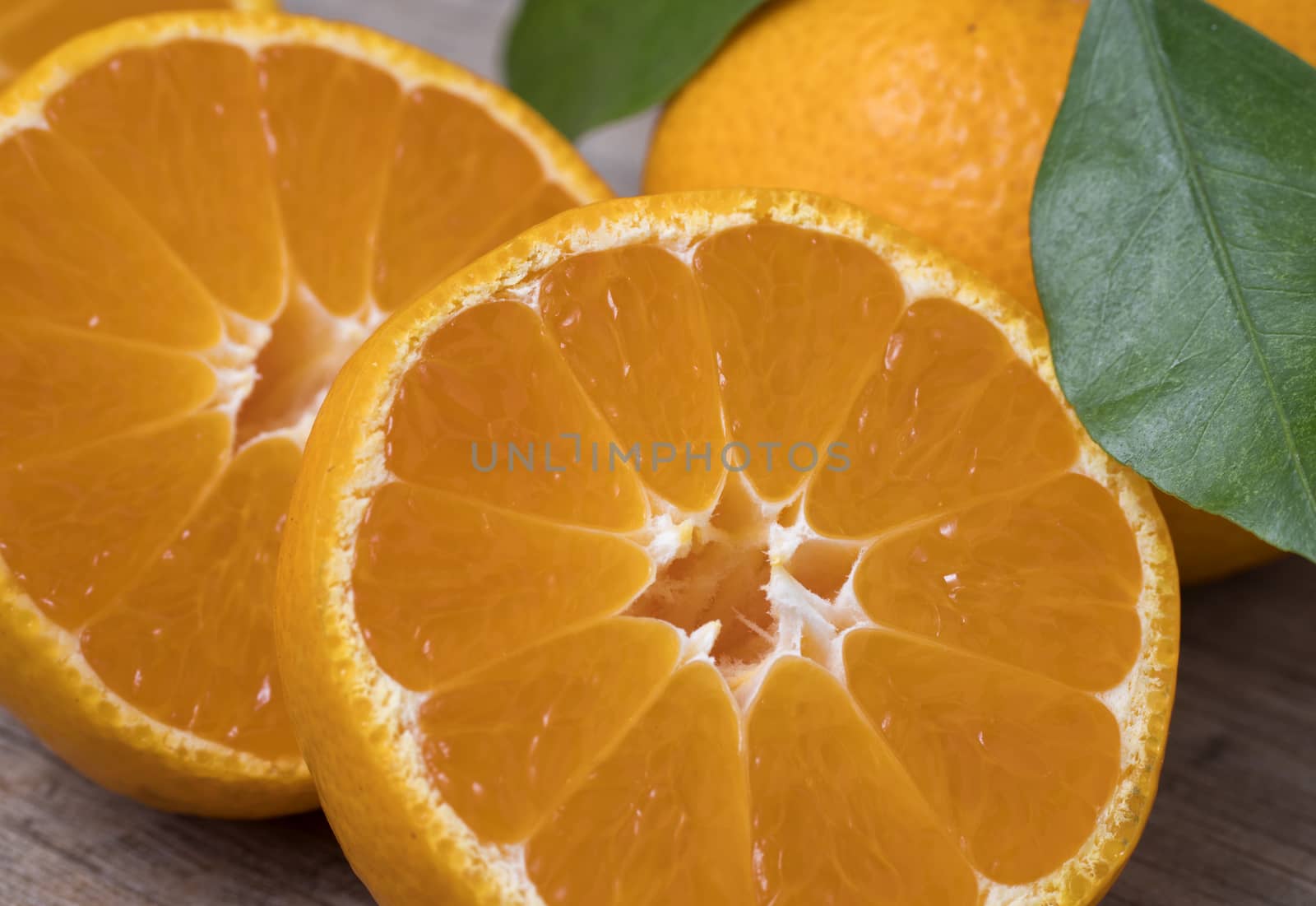 Fresh ripe tangerines with leaves on a wooden background. Close up view.