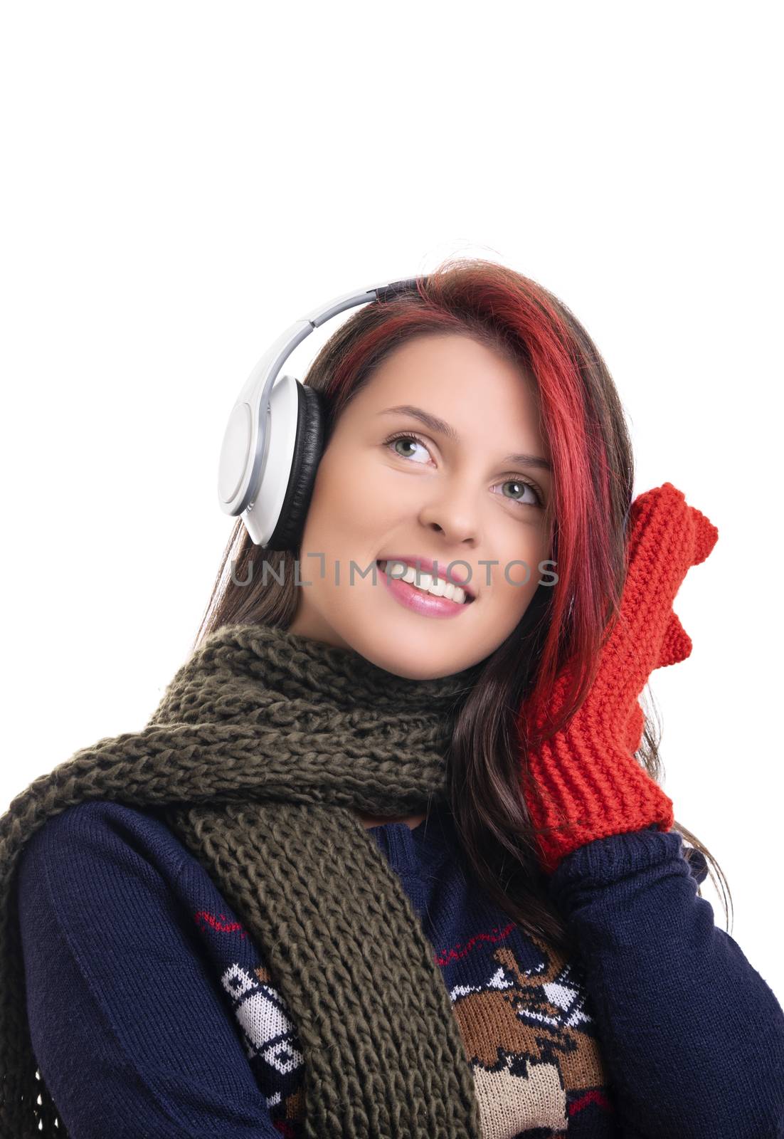 Beautiful smiling young girl with scarf and mittens listening to music on her headphones, isolated on white background.