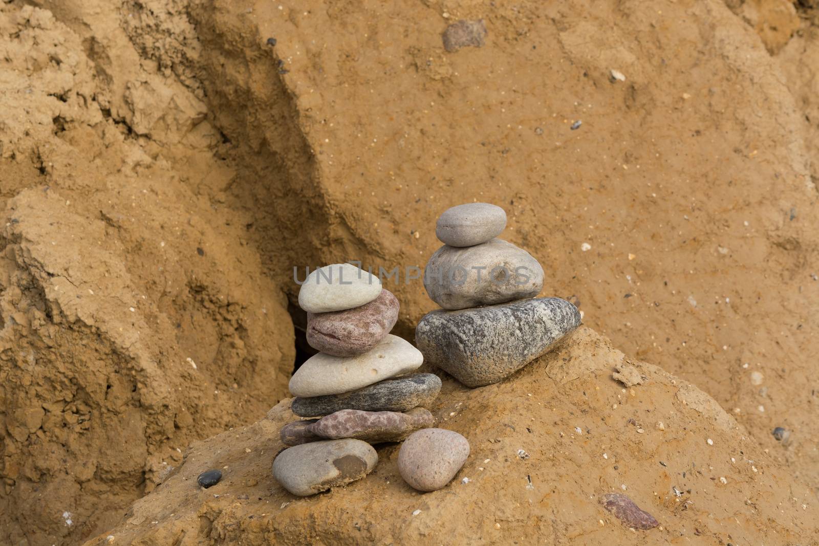 Stones stacked on top of each other on the beach in the background the cliff