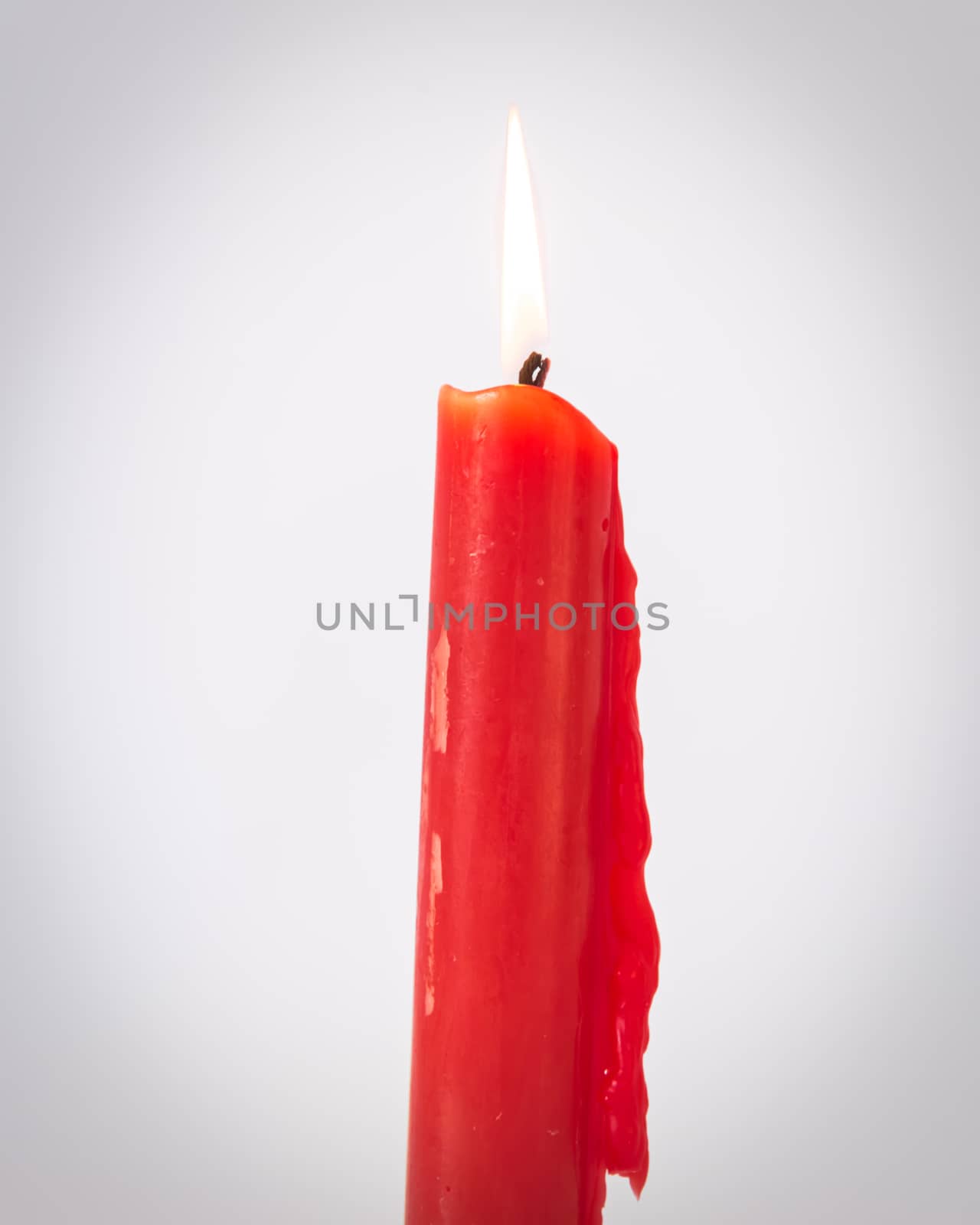 Vintage tone close-up single red burning candle isolated on white background. Popular Asian stick candle for daily and holiday uses.