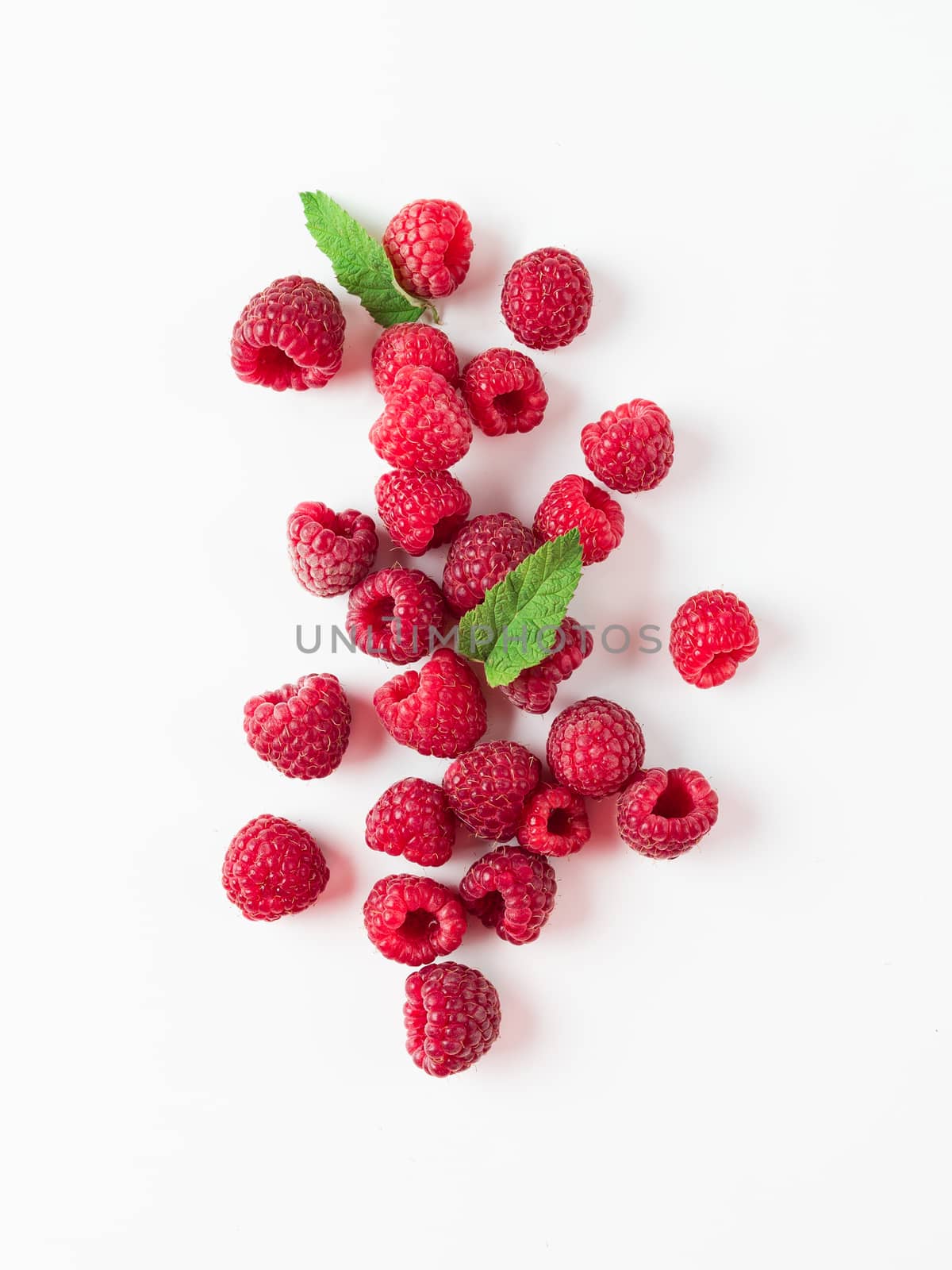 Heap of fresh ripe red raspberries with green leaves on white background. Top view or flat lay. Vertical