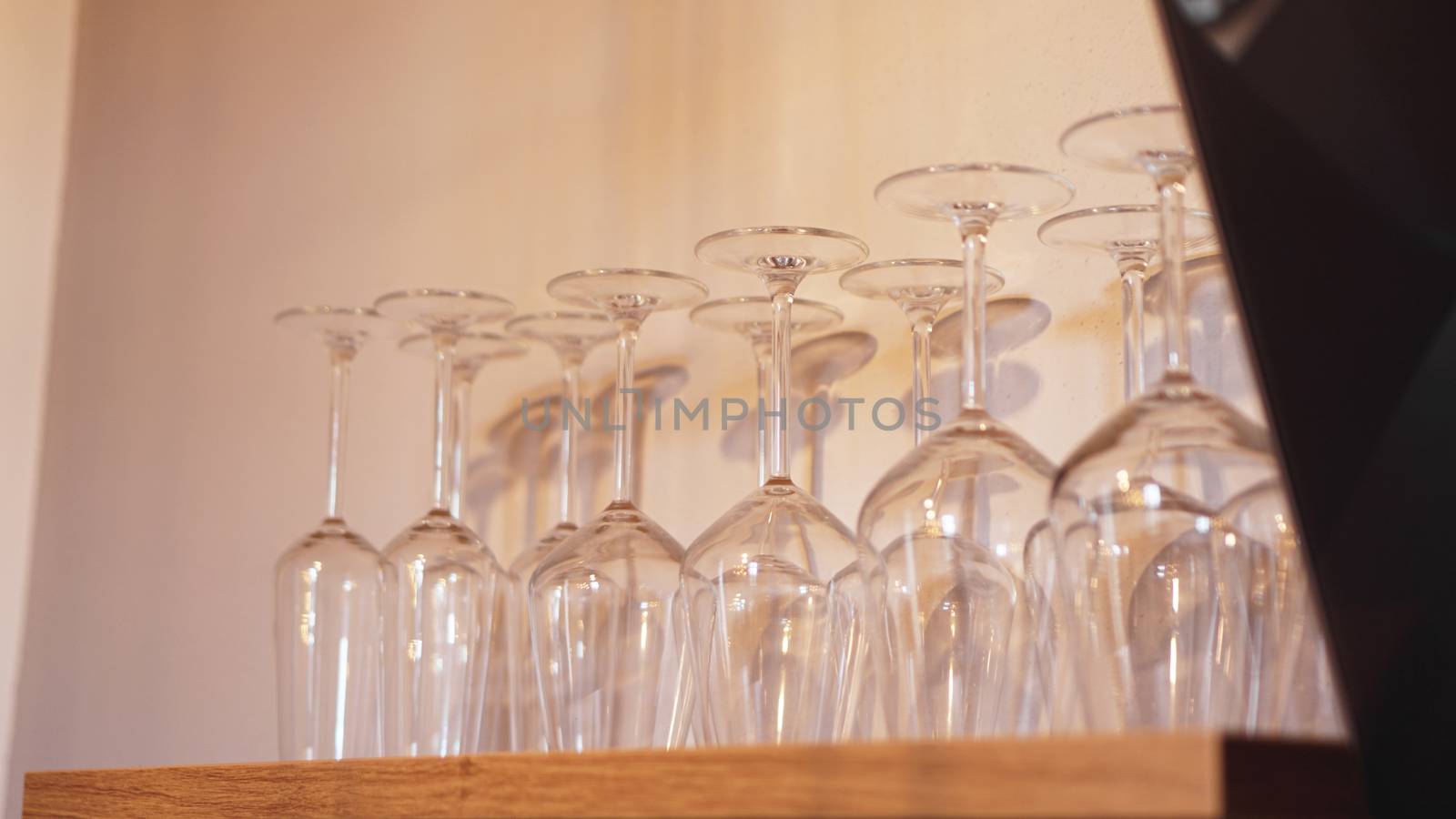 Lots of wine glasses on shelf. Empty wine glasses