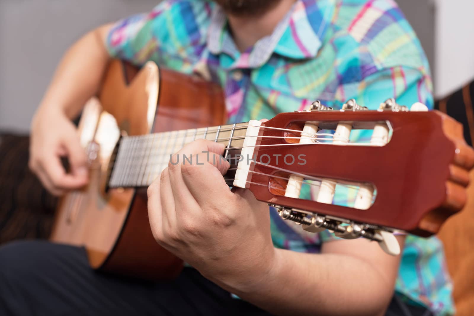 Bearded hipster man hand playing acoustic guitar. Close-up selective focus on hand.