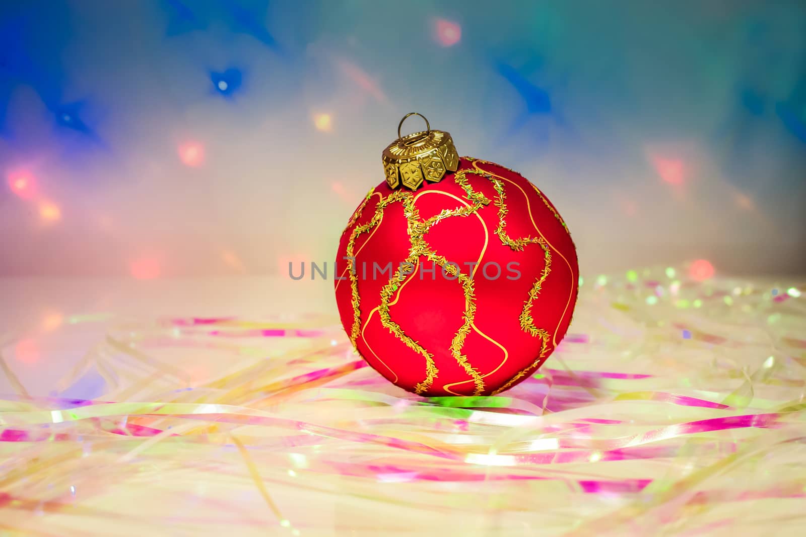 Red Christmas ball on the table with the tinsel on the background lights