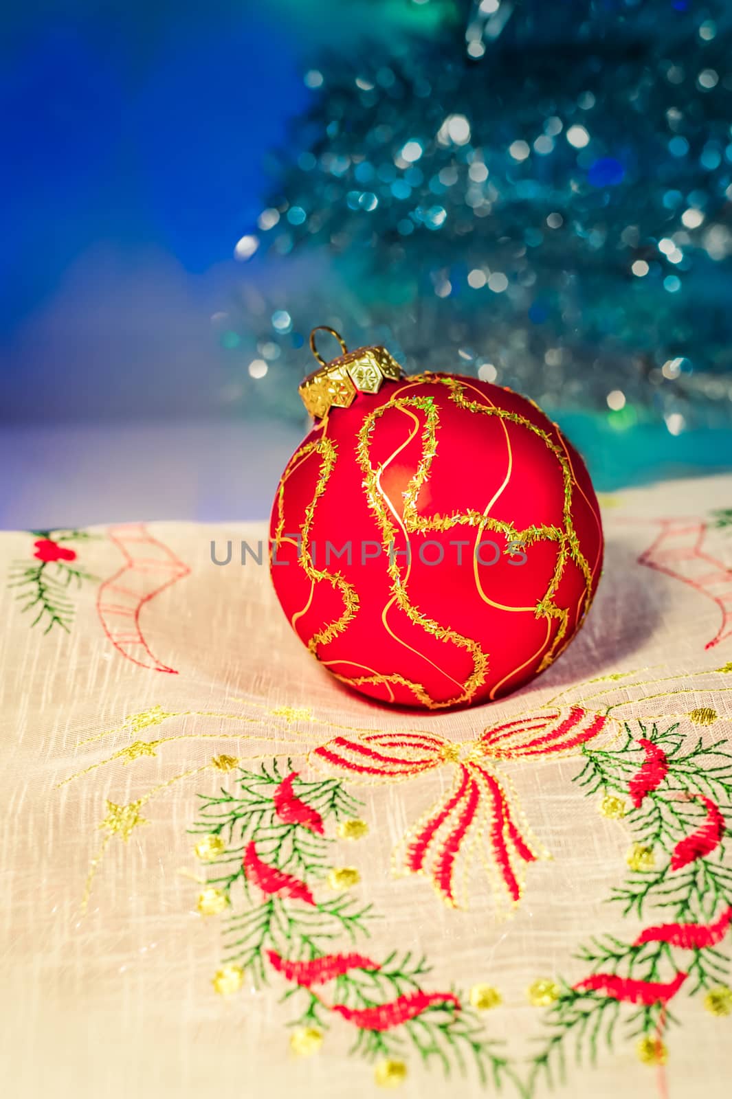 Red Christmas ball on a napkin on the background of Christmas trees and lights