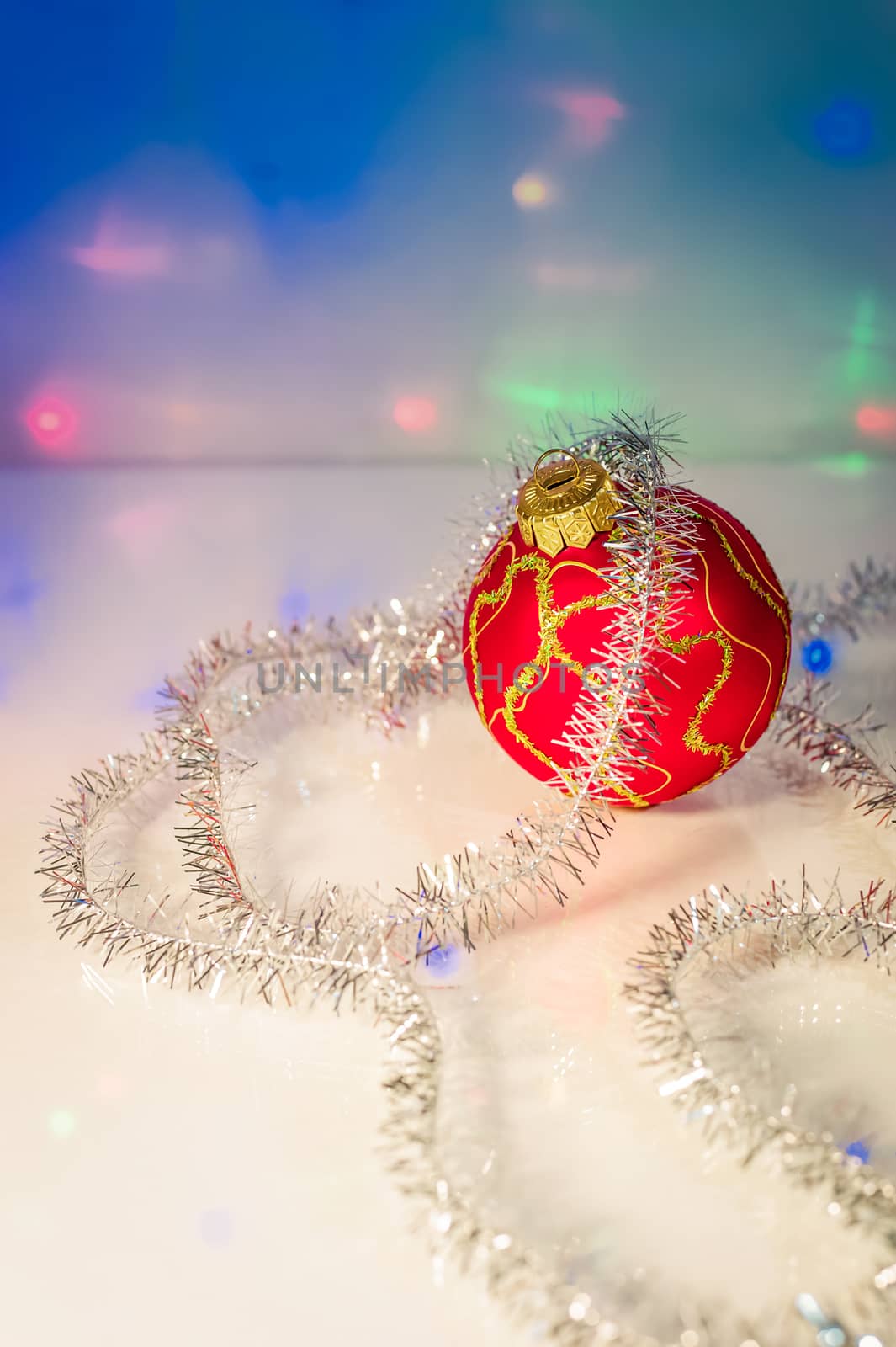 Red Christmas-tree ball and tinsel on the background blurry lights garland