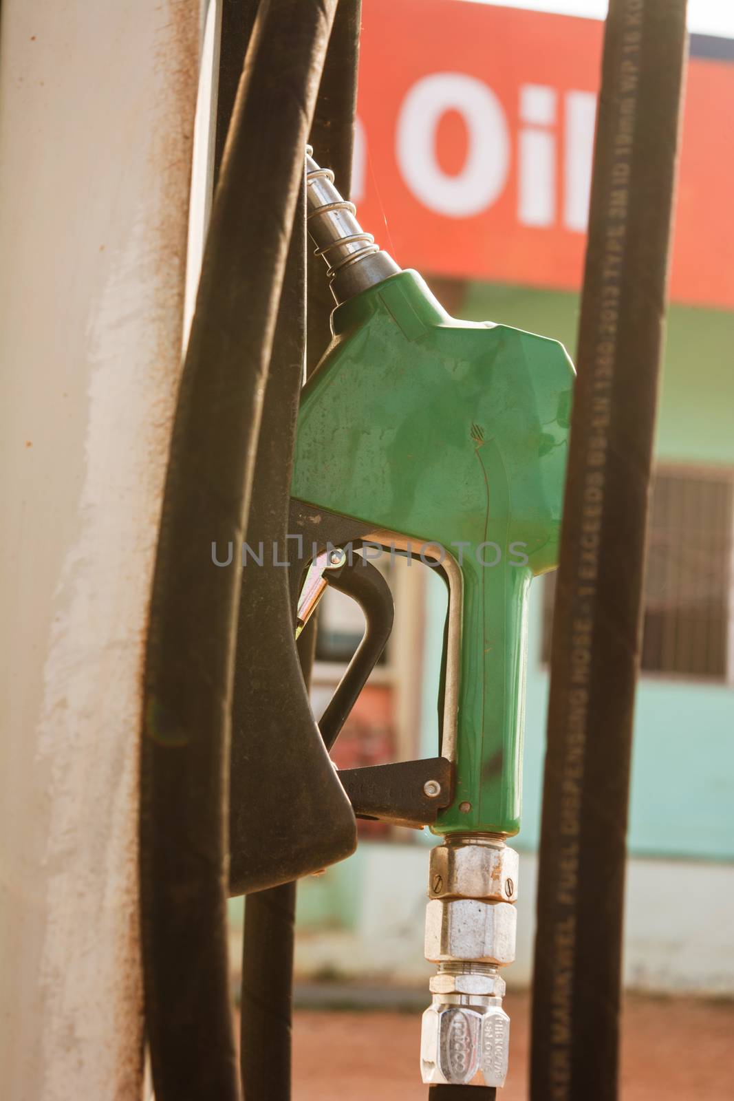 Fuel oil gasoline dispenser at petrol filling station.Holding fuel nozzle to refuel gasoline for car. by lakshmiprasad.maski@gmai.com