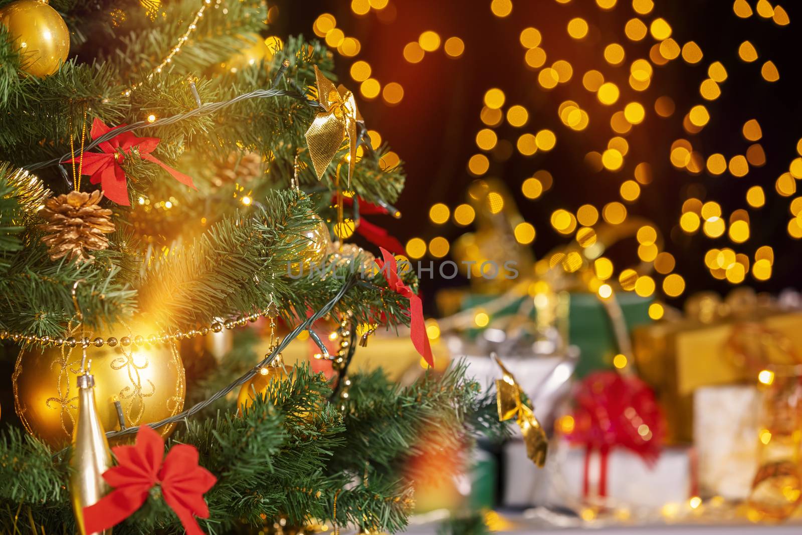 Stack of packed gift boxes under Christmas tree against particles lights. Lots of Christmas gifts under the tree. Selective focus on the yellow globe!