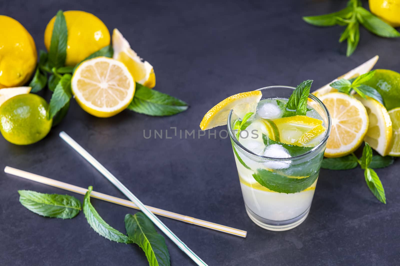 Top view of fresh lemonade with mint and ice in glasses on black background. Focus on ice.