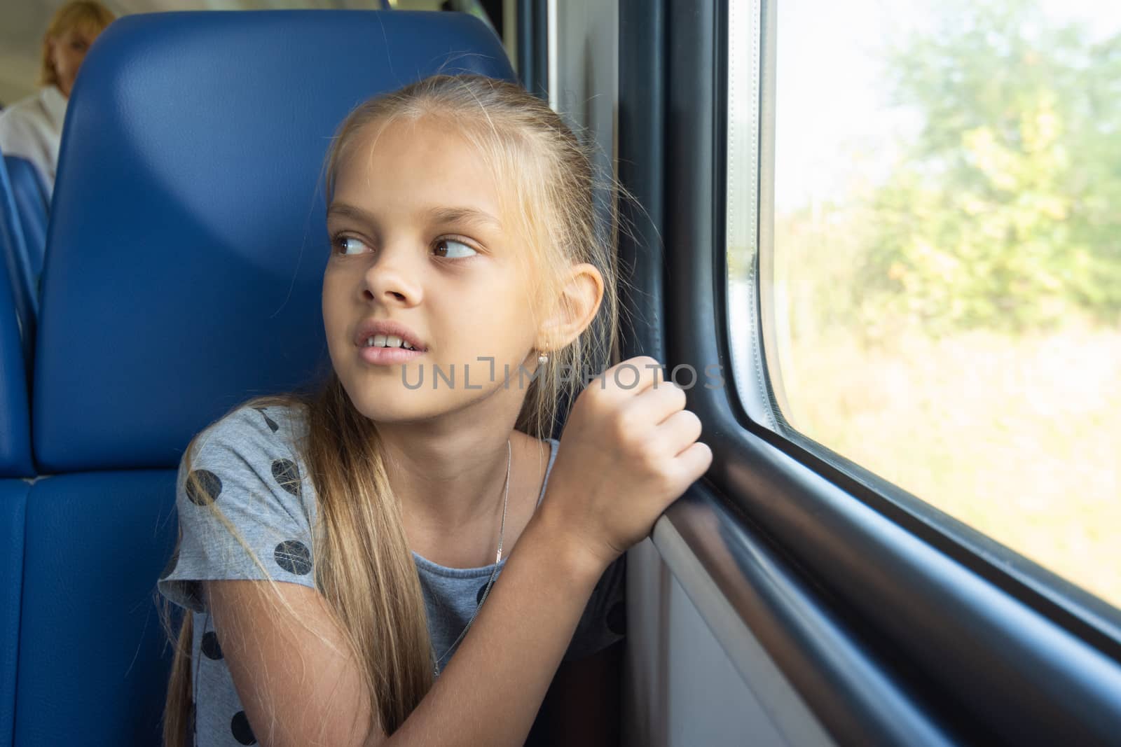 Girl sitting by the window in an electric train car