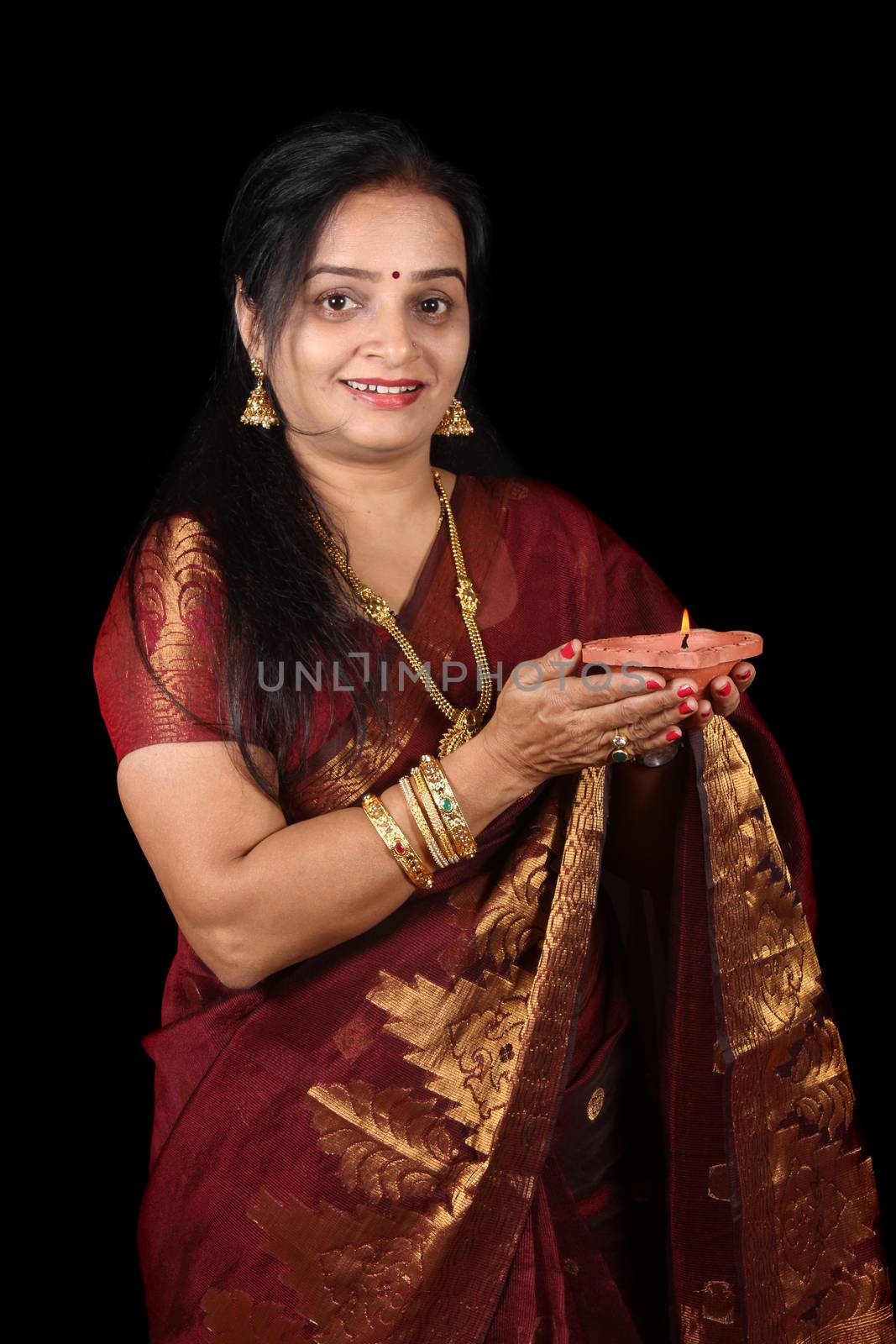 A beautiful Indian woman smiling holding in Diwali due to happiness in Diwali, on black studio background.
