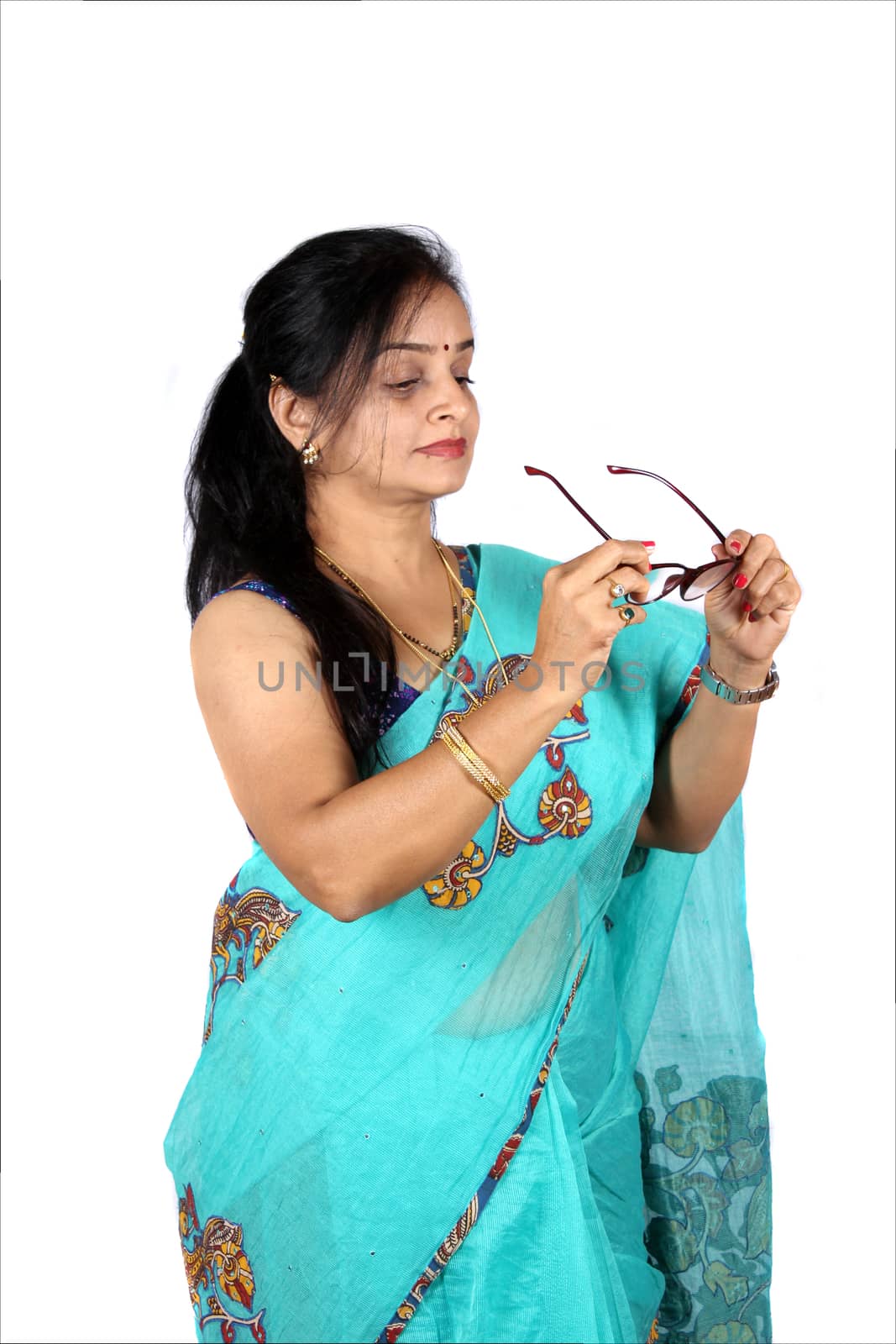 A beautiful Indian middleaged woman wearing her glasses, on white studio background.