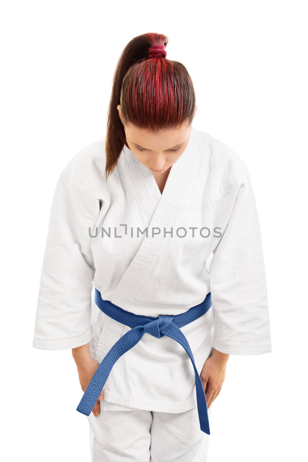 A portrait of a young girl in a white kimono with blue belt bowing, isolated on white background.