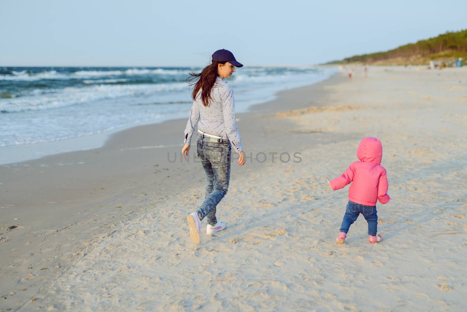 Mother and little daughter playing on the beach. Authentic image.
