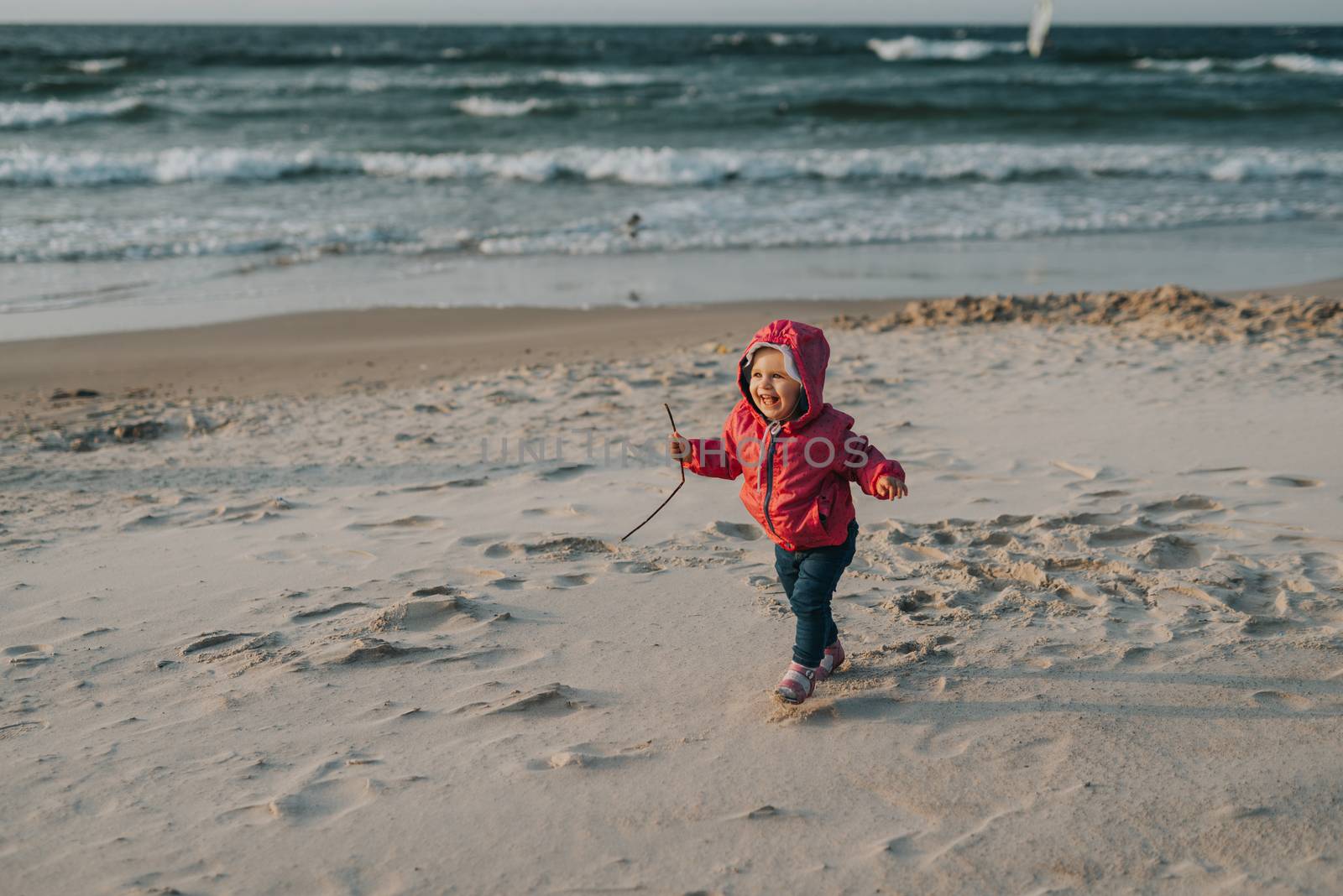 Adorable toddler girl on a sunny sand beach. Authentic childhood