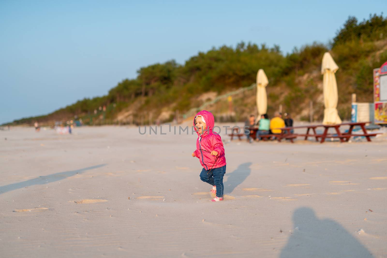 Adorable toddler girl on a sunny sand beach. Authentic childhood