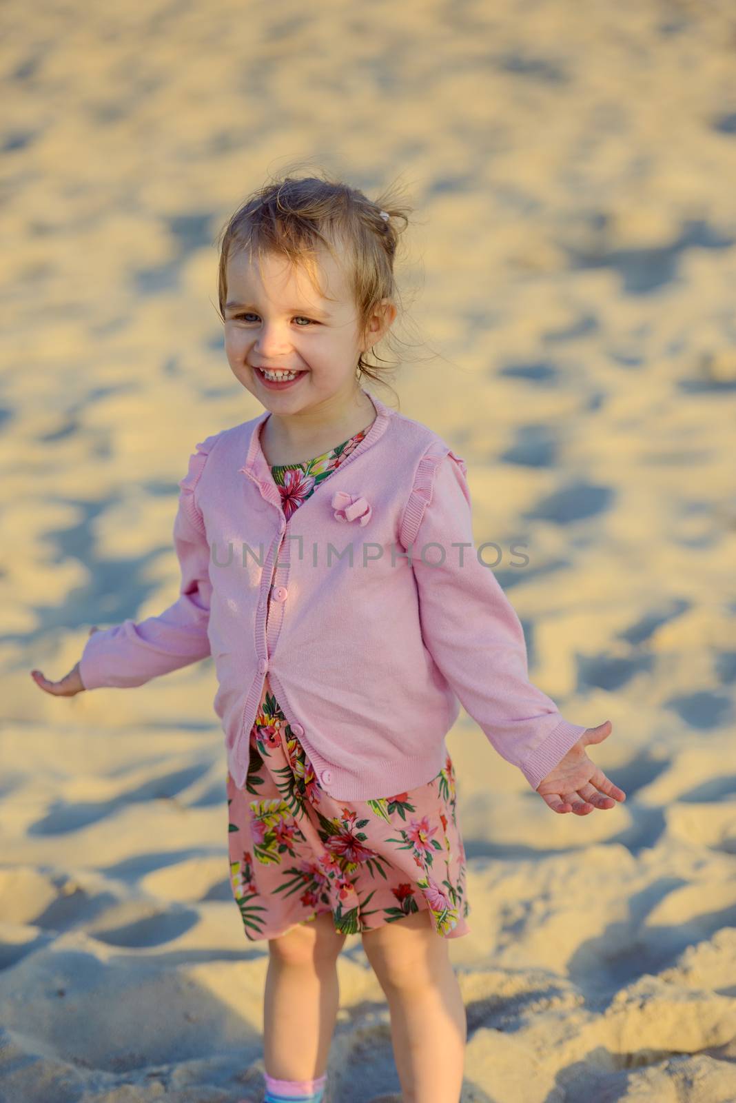 Adorable toddler girl on a sunny sand beach. Authentic childhood