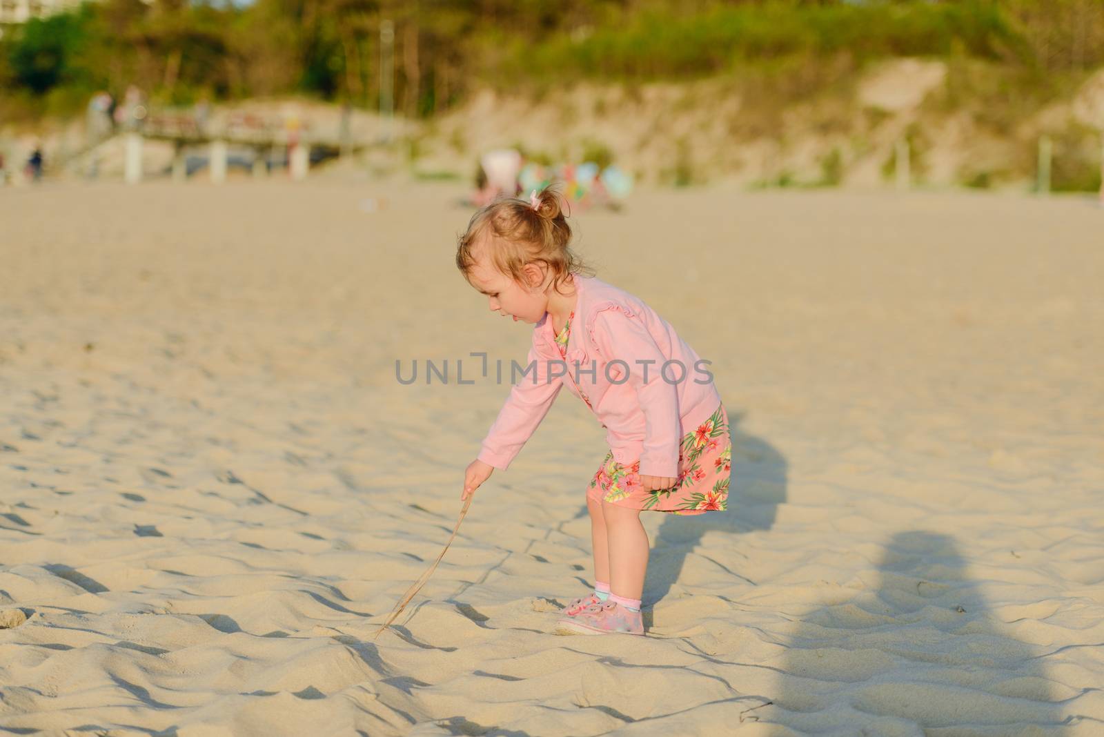 Adorable toddler girl on a sunny sand beach. Authentic childhood