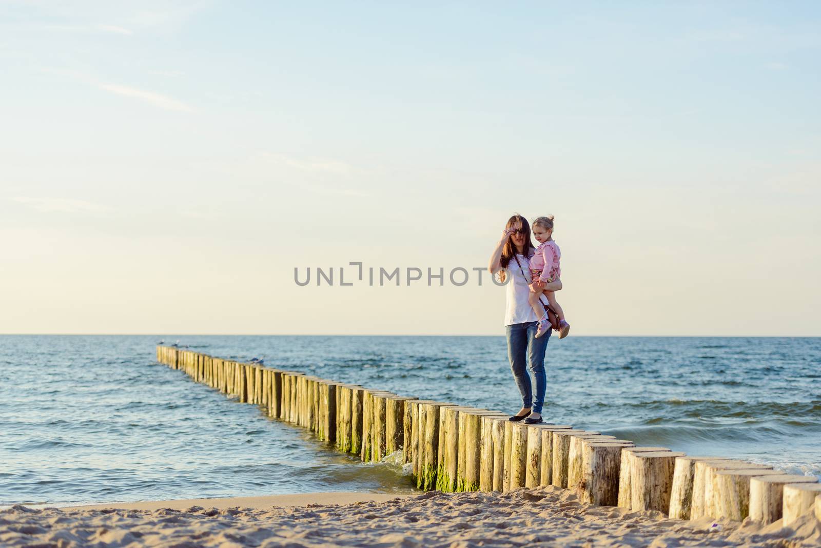 Mother and little daughter playing on the beach. Authentic image.