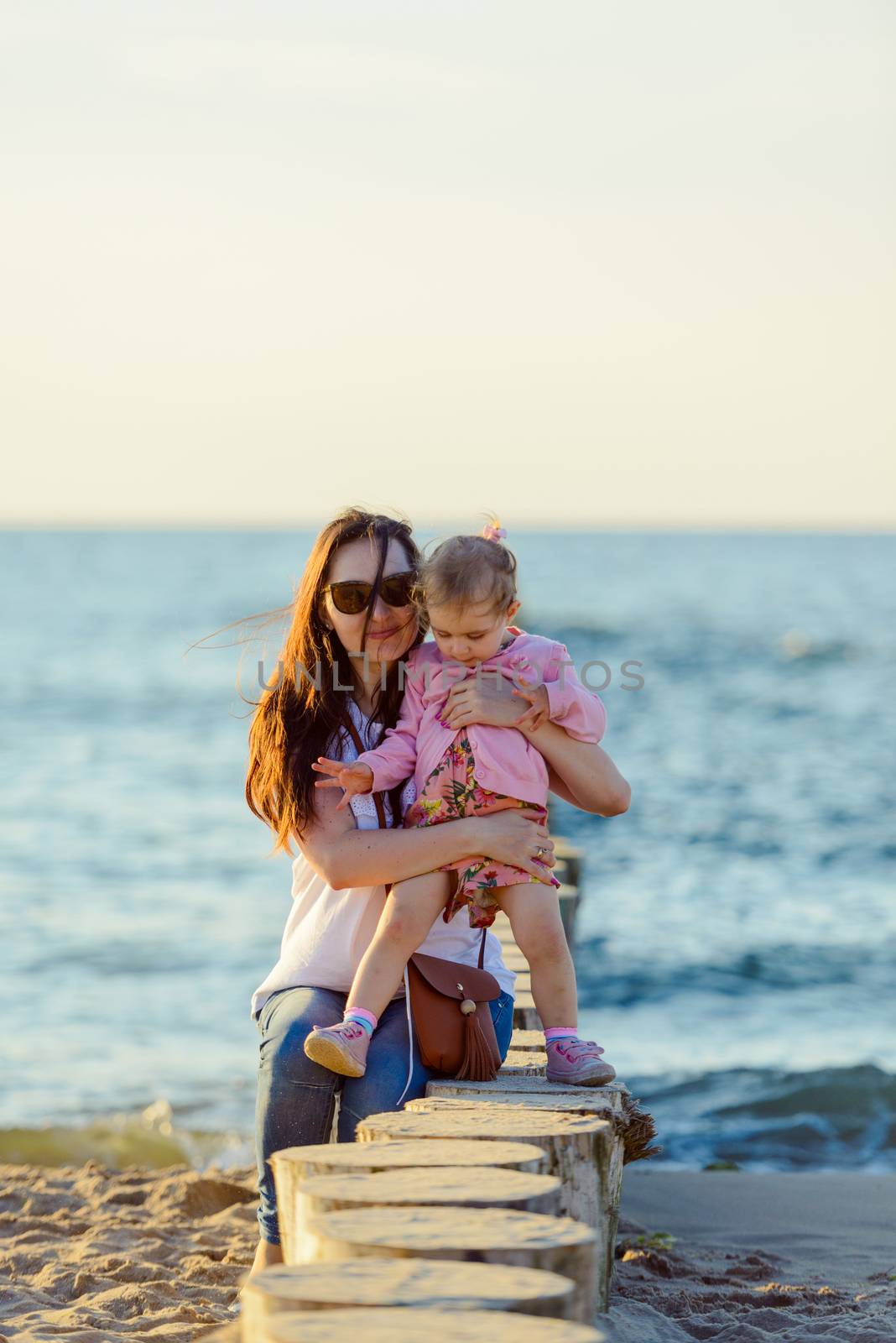 Mother and little daughter playing on the beach. Authentic image.