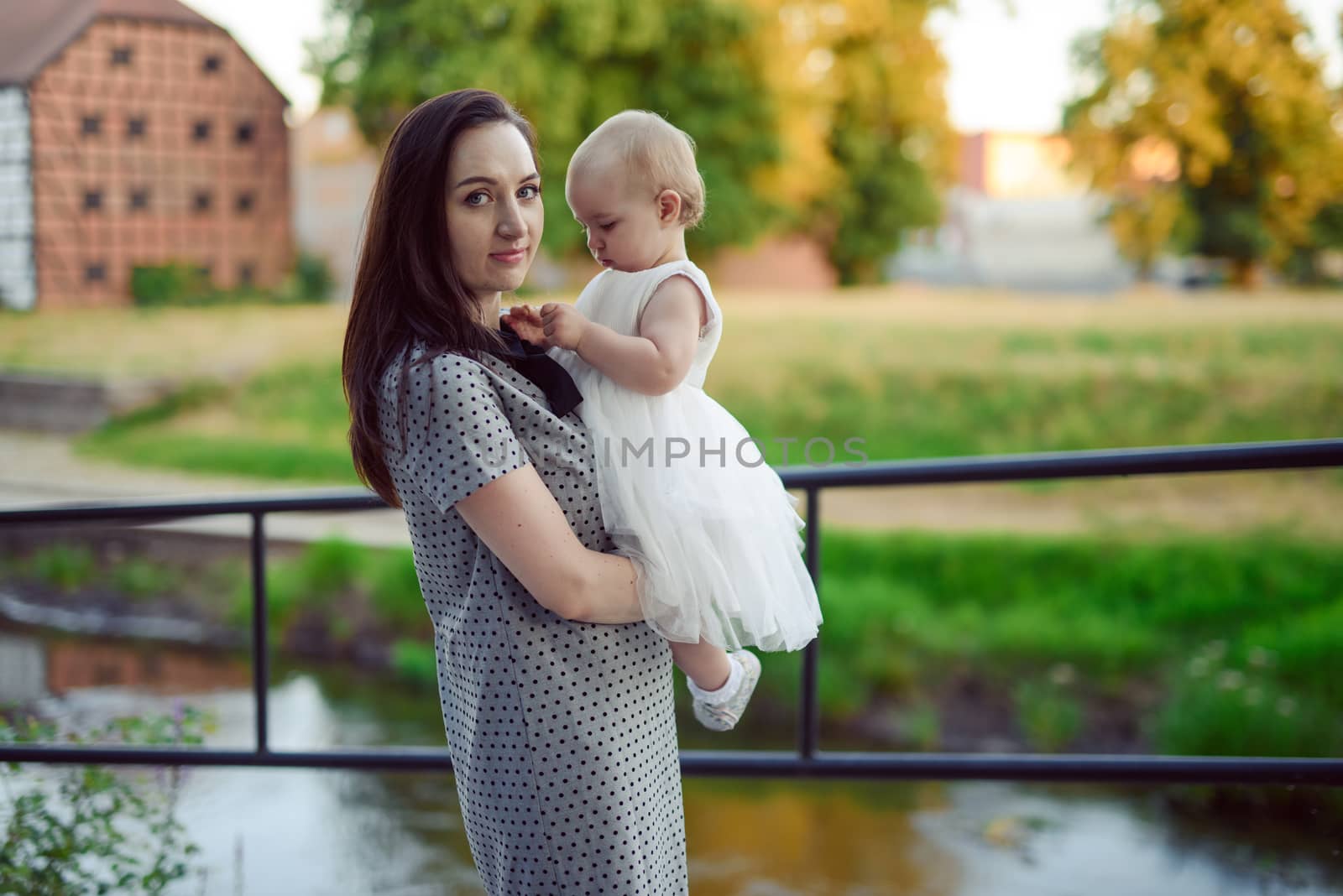 Happy mother and daughter in the park. Beauty nature scene with family outdoor lifestyle. Happy family resting together on the green grass, having fun outdoor. Happiness and harmony in family life.