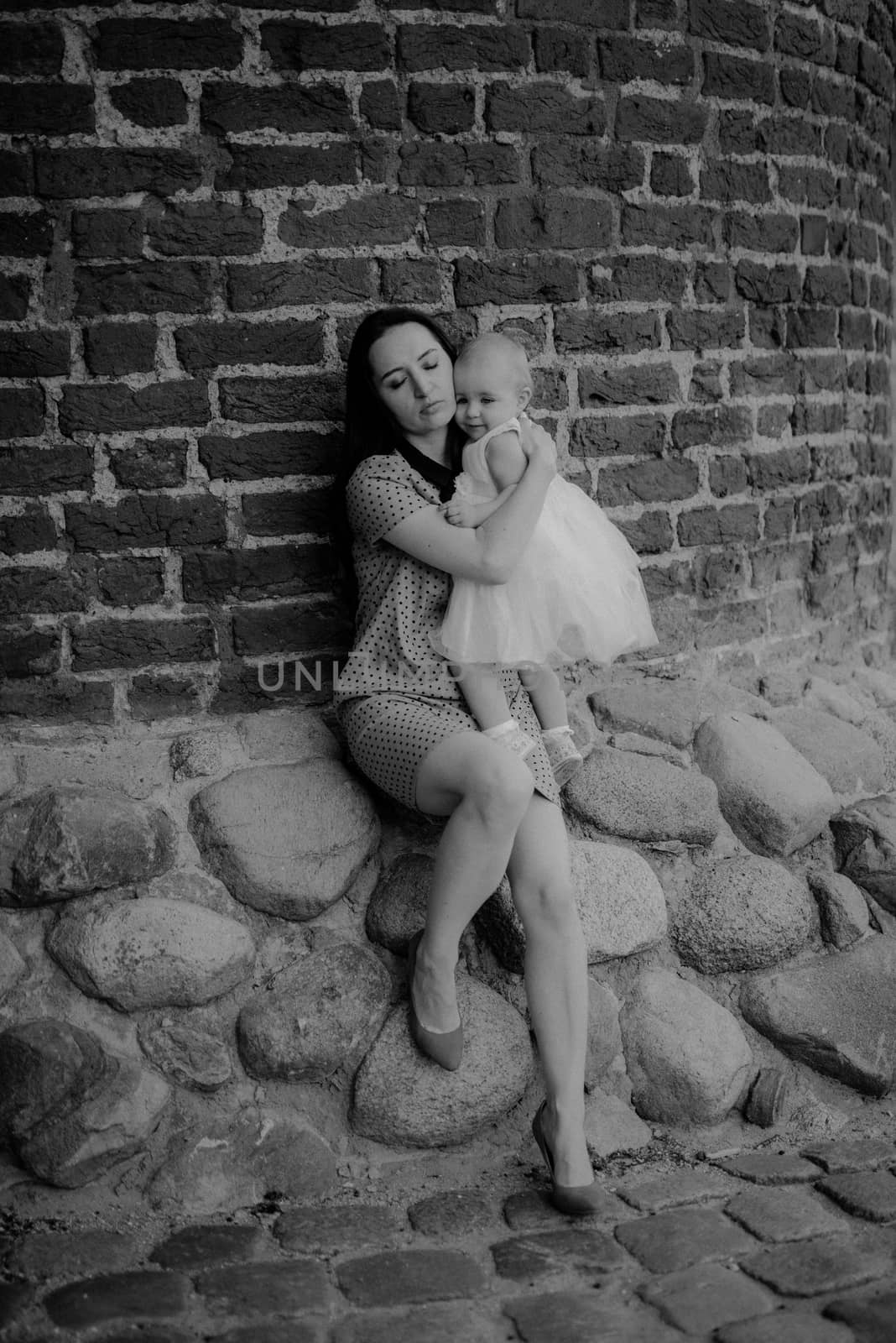 Happy mother and daughter in the park. Beauty nature scene with family outdoor lifestyle. Happy family resting together on the green grass, having fun outdoor. Happiness and harmony in family life.