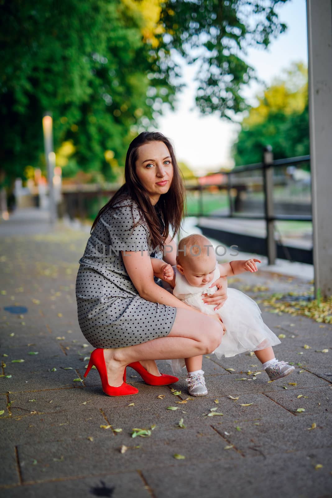 Happy mother and daughter in the park. Beauty nature scene with family outdoor lifestyle. Happy family resting together on the green grass, having fun outdoor. Happiness and harmony in family life.