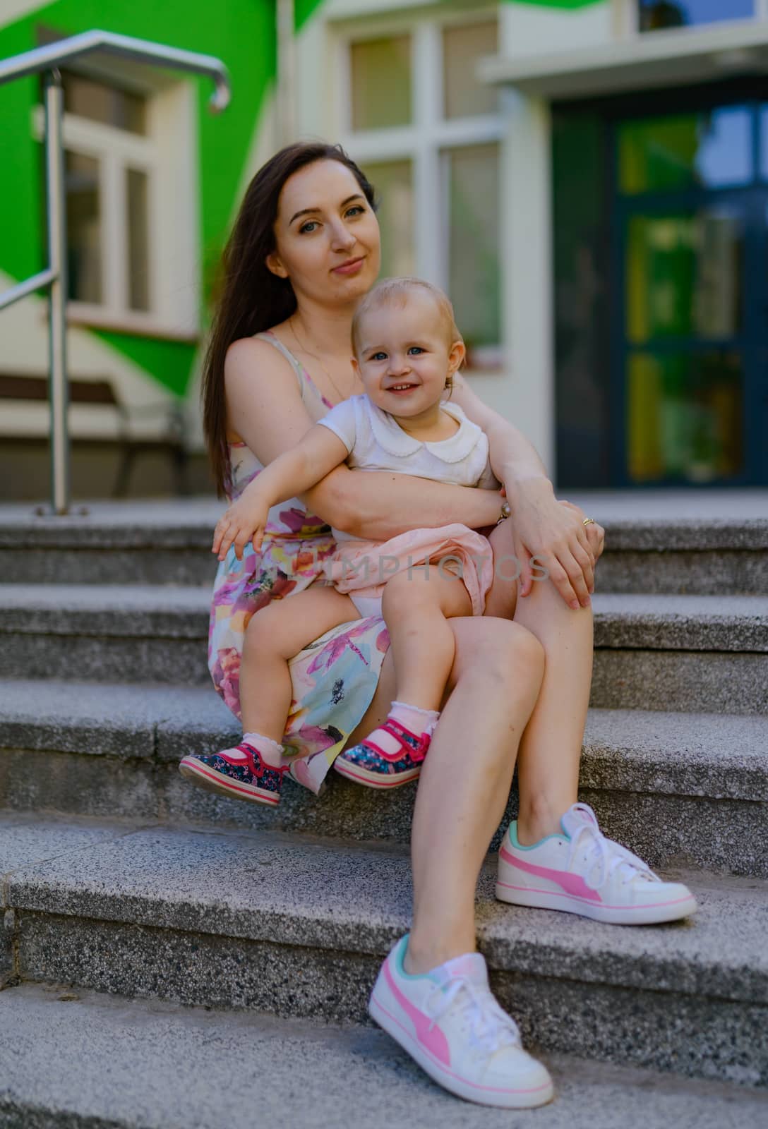 Happy mother and daughter in the park. Beauty nature scene with family outdoor lifestyle. Happy family resting together on the green grass, having fun outdoor. Happiness and harmony in family life.