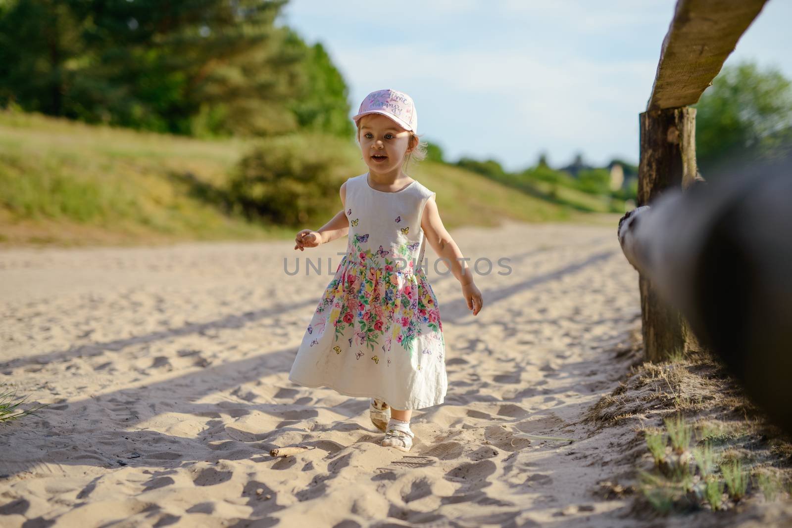Adorable toddler girl on a sunny sand beach. Authentic childhood
