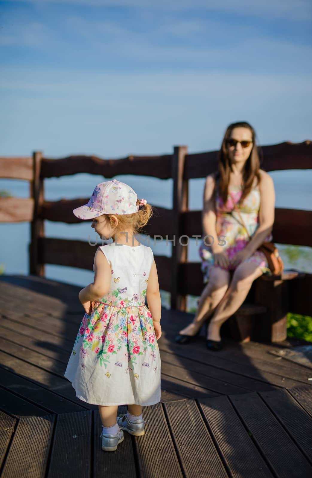 Happy mother and daughter in the park. Beauty nature scene with family outdoor lifestyle. Happy family resting together on the green grass, having fun outdoor. Happiness and harmony in family life.