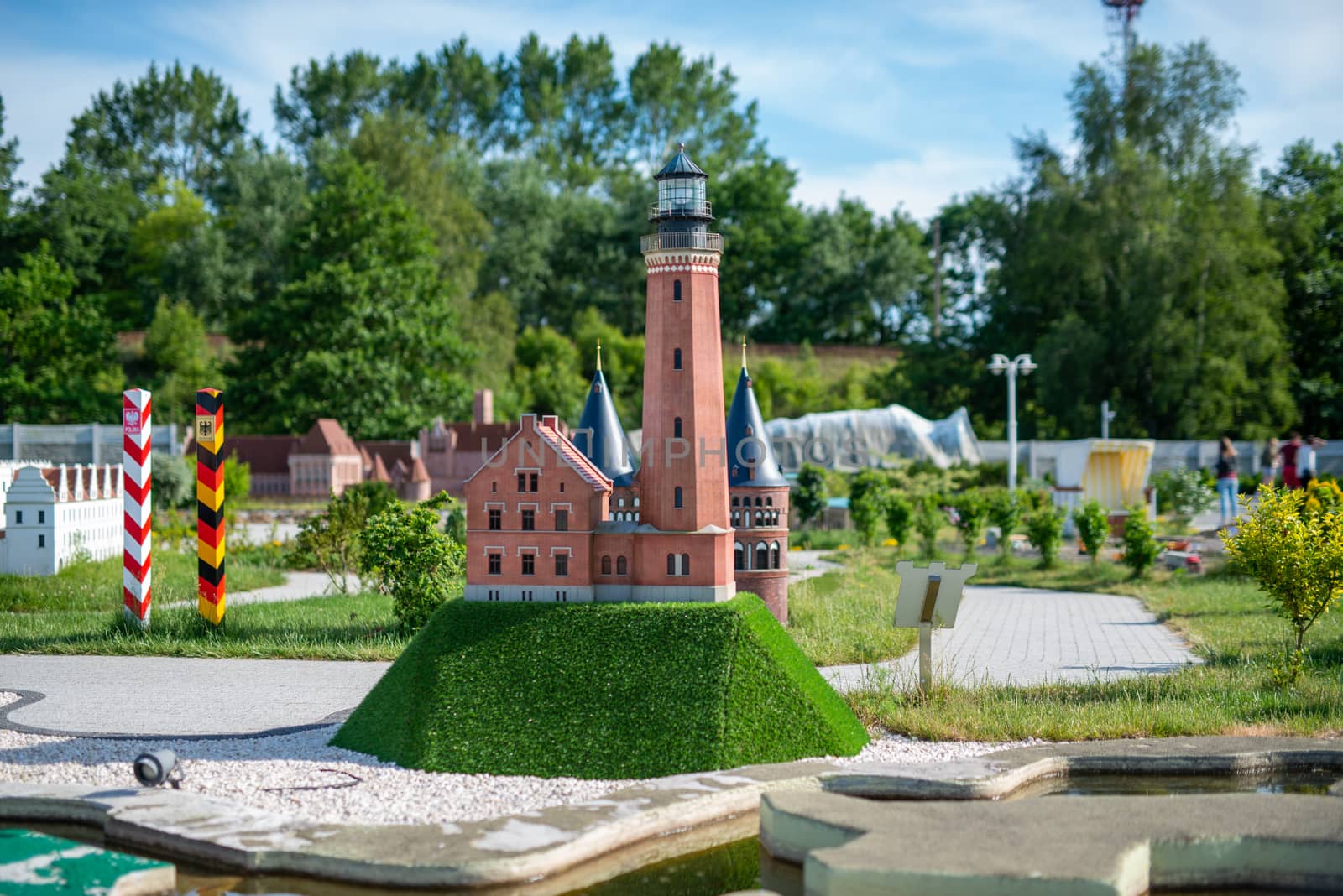 toy lighthouse, brick toy lighthouse and yellow sailboat with sand beach background