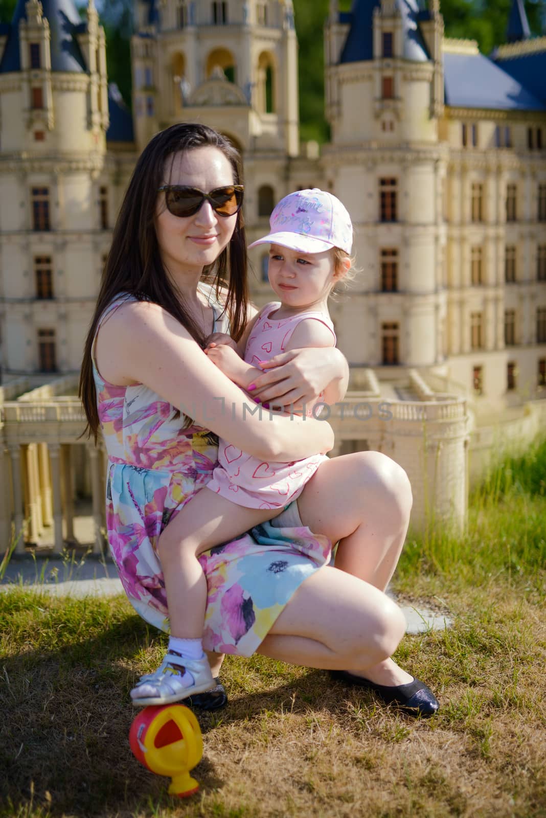 Happy mother and daughter in the park. Beauty nature scene with family outdoor lifestyle. Happy family resting together on the green grass, having fun outdoor. Happiness and harmony in family life.