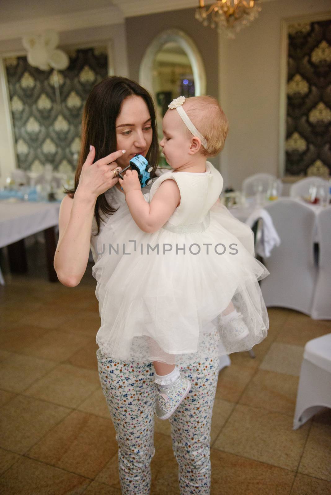 Baby girl 1 year old party time. Mother holding his baby girl on hand. Birthday party. Authentic childhood.