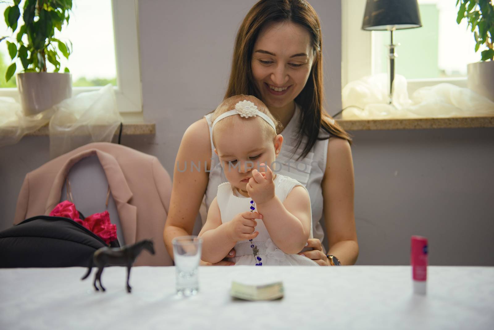 Baby girl 1 year old party time. Mother holding his baby girl on hand. Birthday party. Authentic childhood.