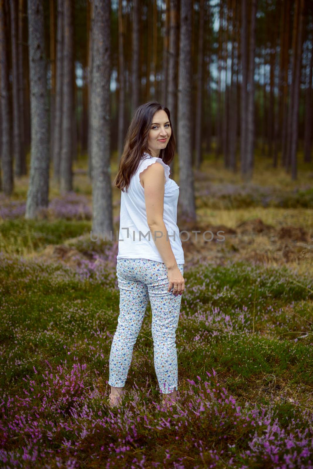 a photo of woman in the forest where the purple heather blooms. copy space. authentic image. by Brejeq