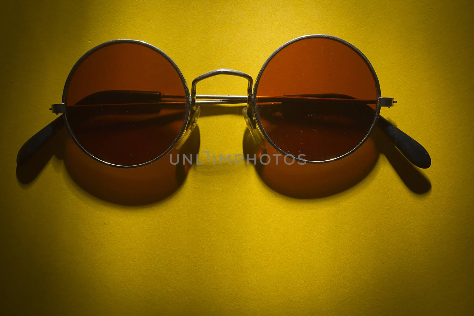 Round sunglasses on the table with yellow coating