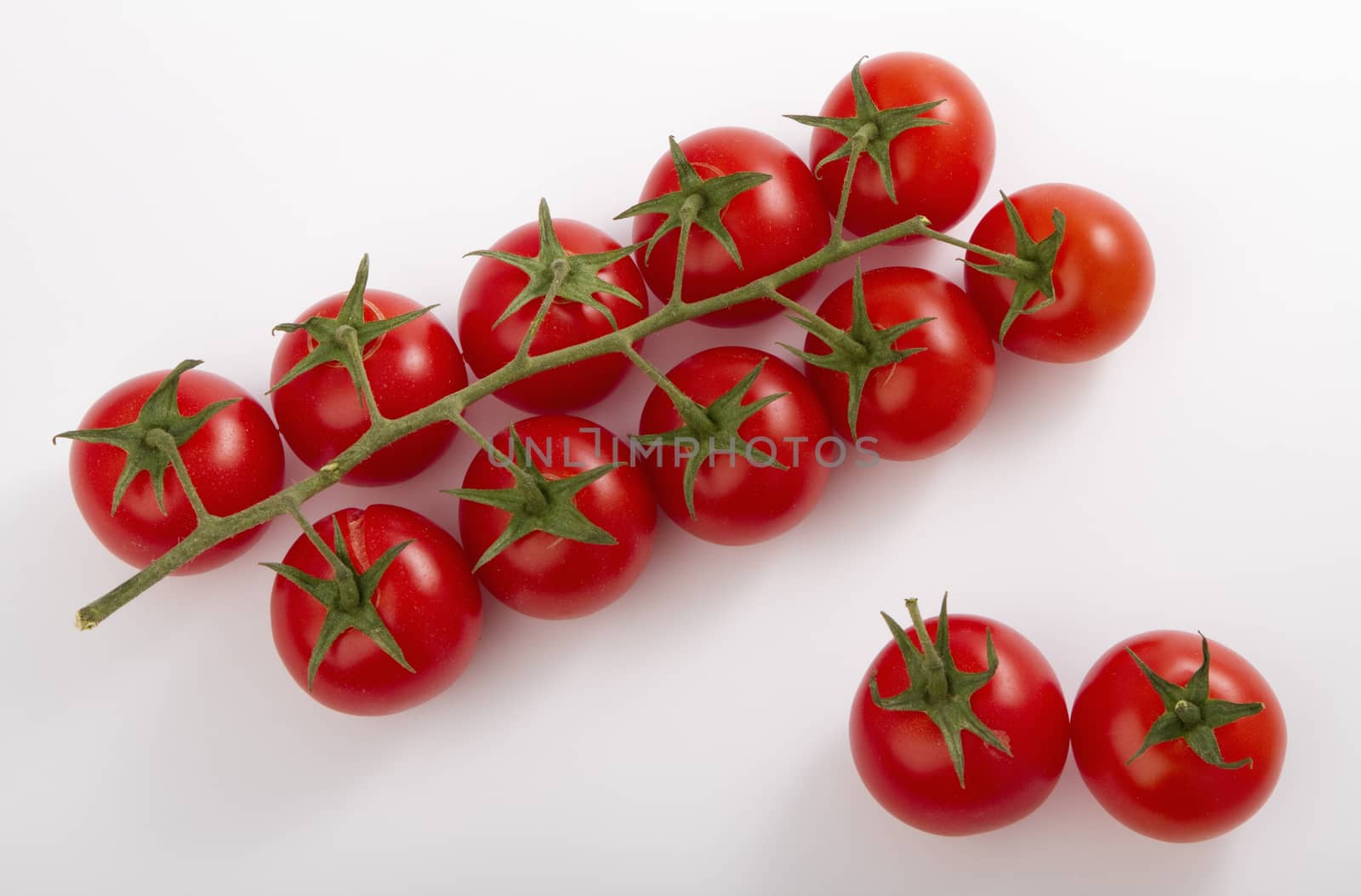 ripe cherry tomatoes on a branch, isolated on white.