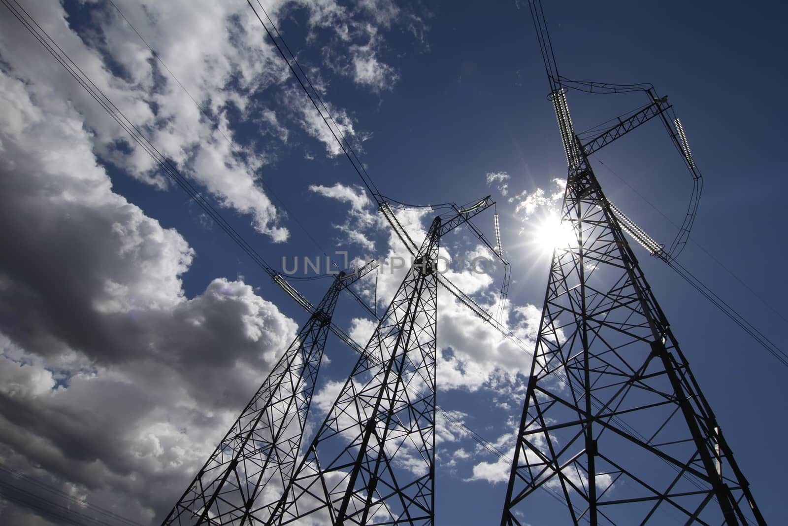 wide angle view of high voltage power pylons on against sky