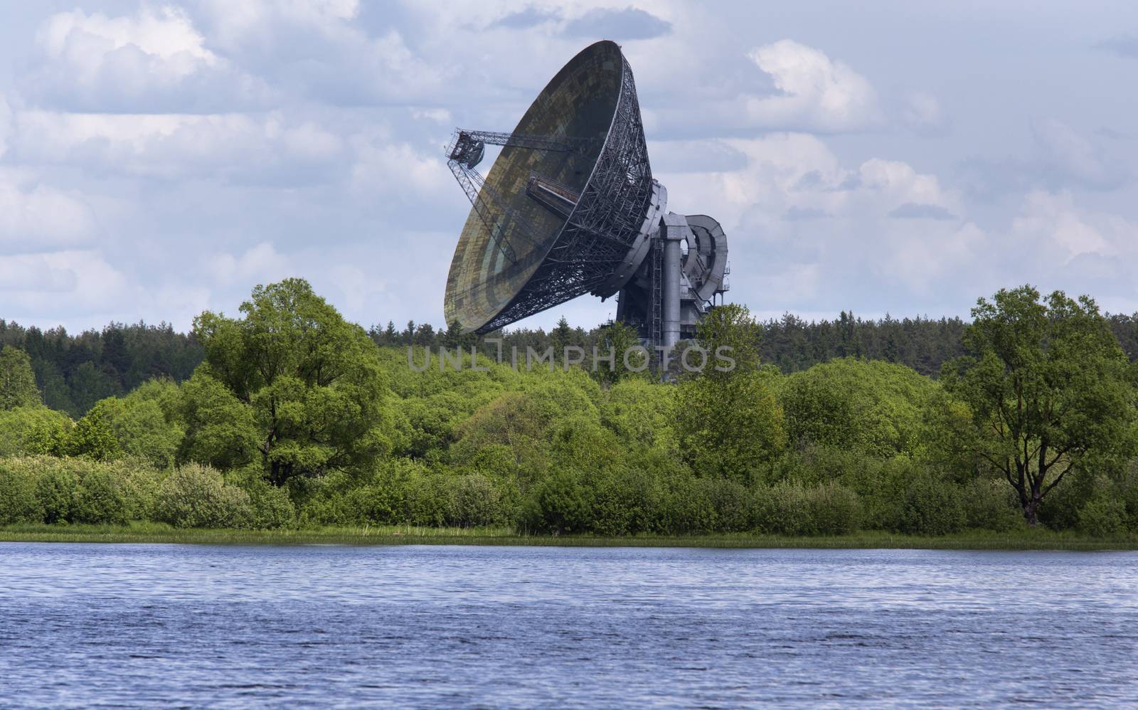 Huge satellite dish aimed at the sky, stands near river bank in Kaljazin, Russia.