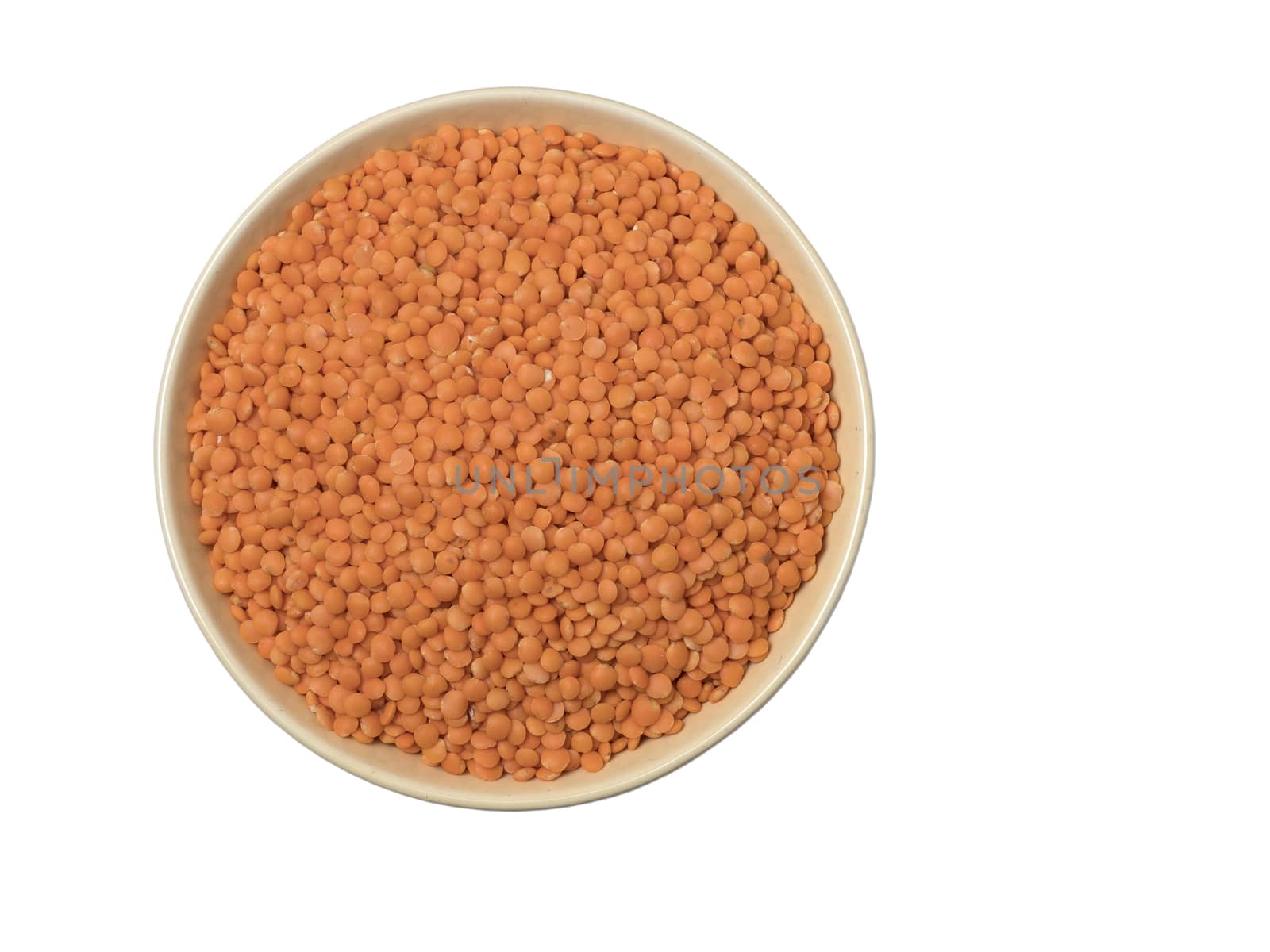 Bowl of red split lentil isolated on white background, top view.