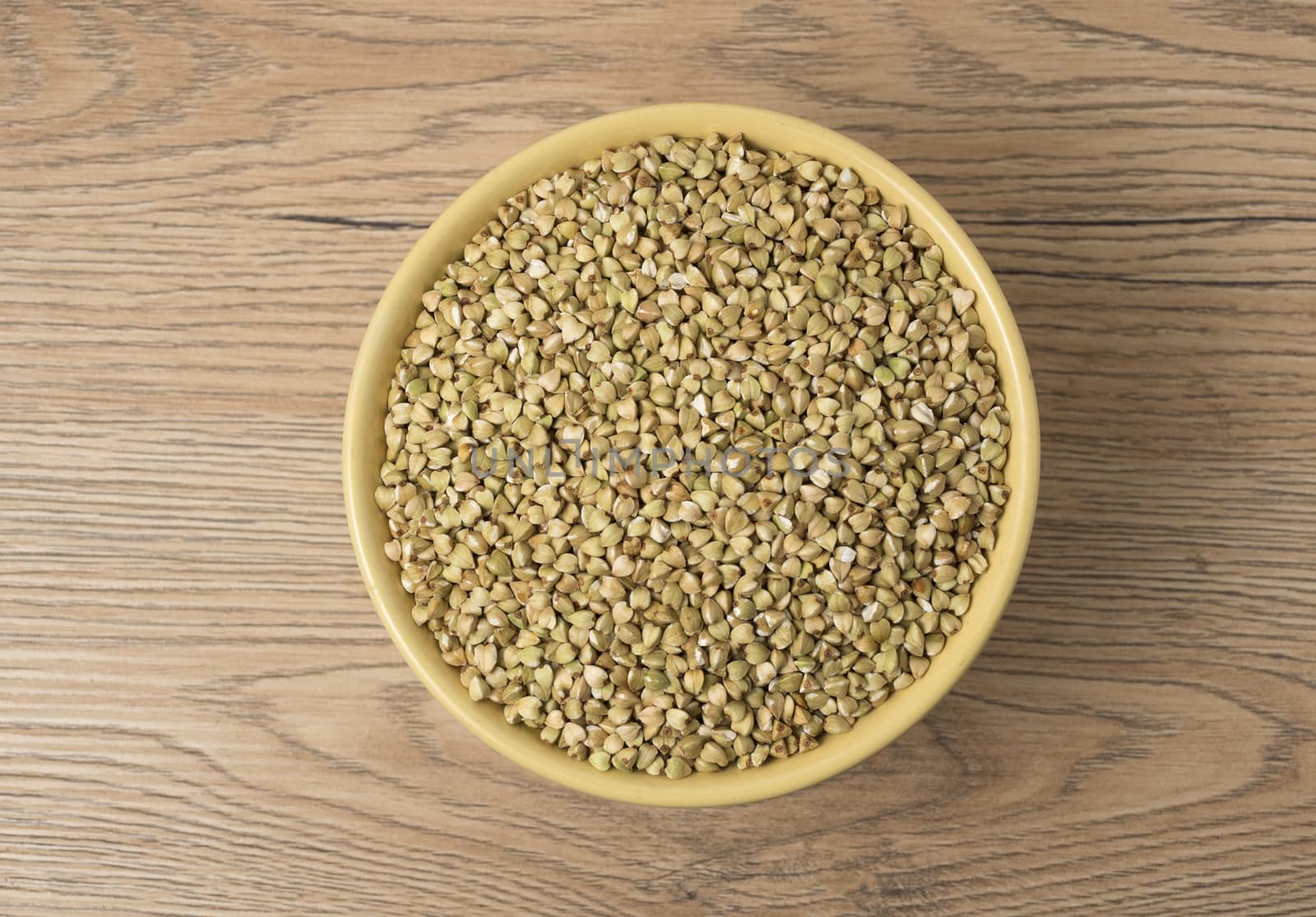 Natural fresh green buckwheat in ceramic bowl on wooden background. Top view.