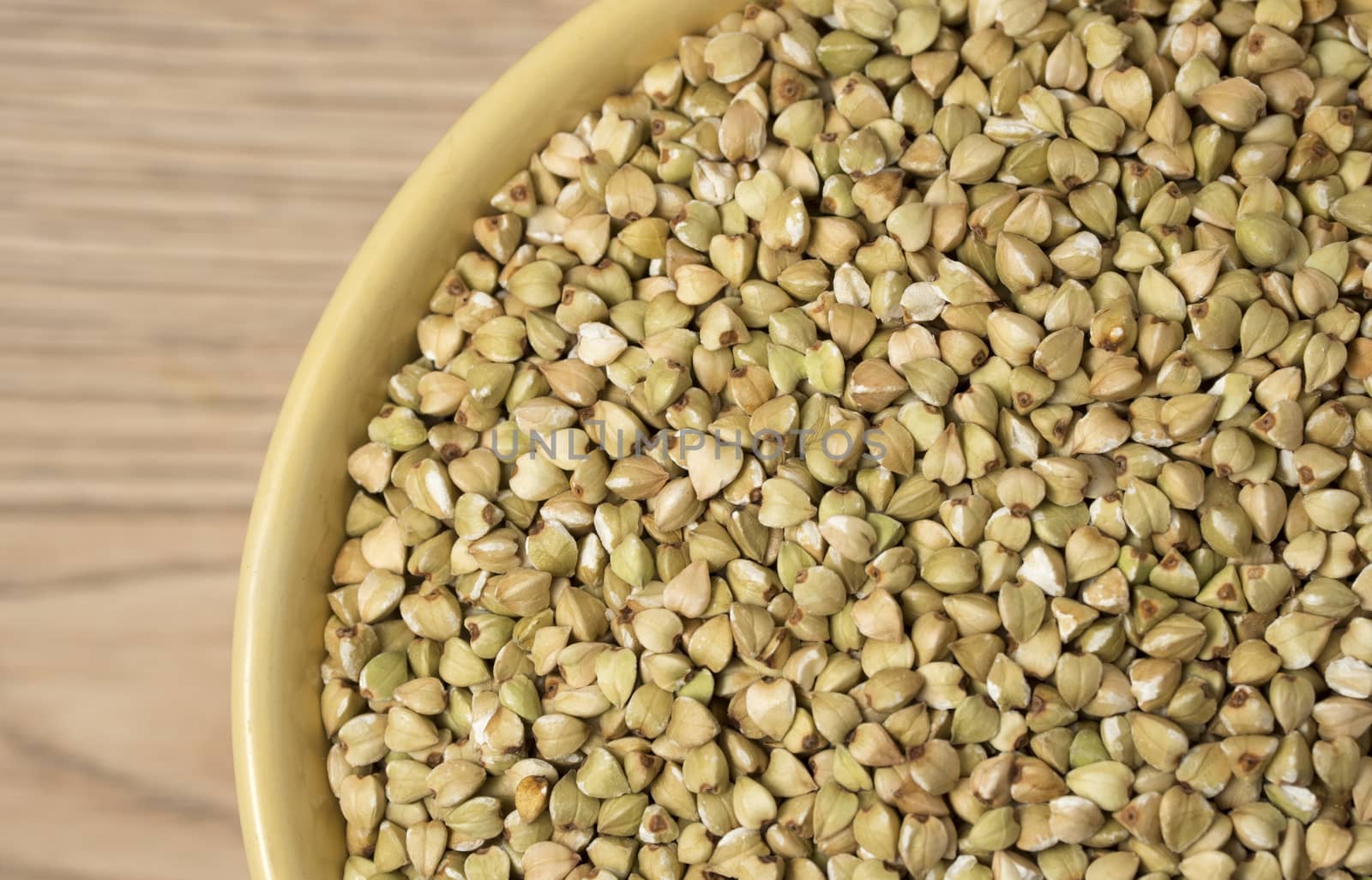Natural fresh green buckwheat in ceramic bowl on wooden background. Top view.