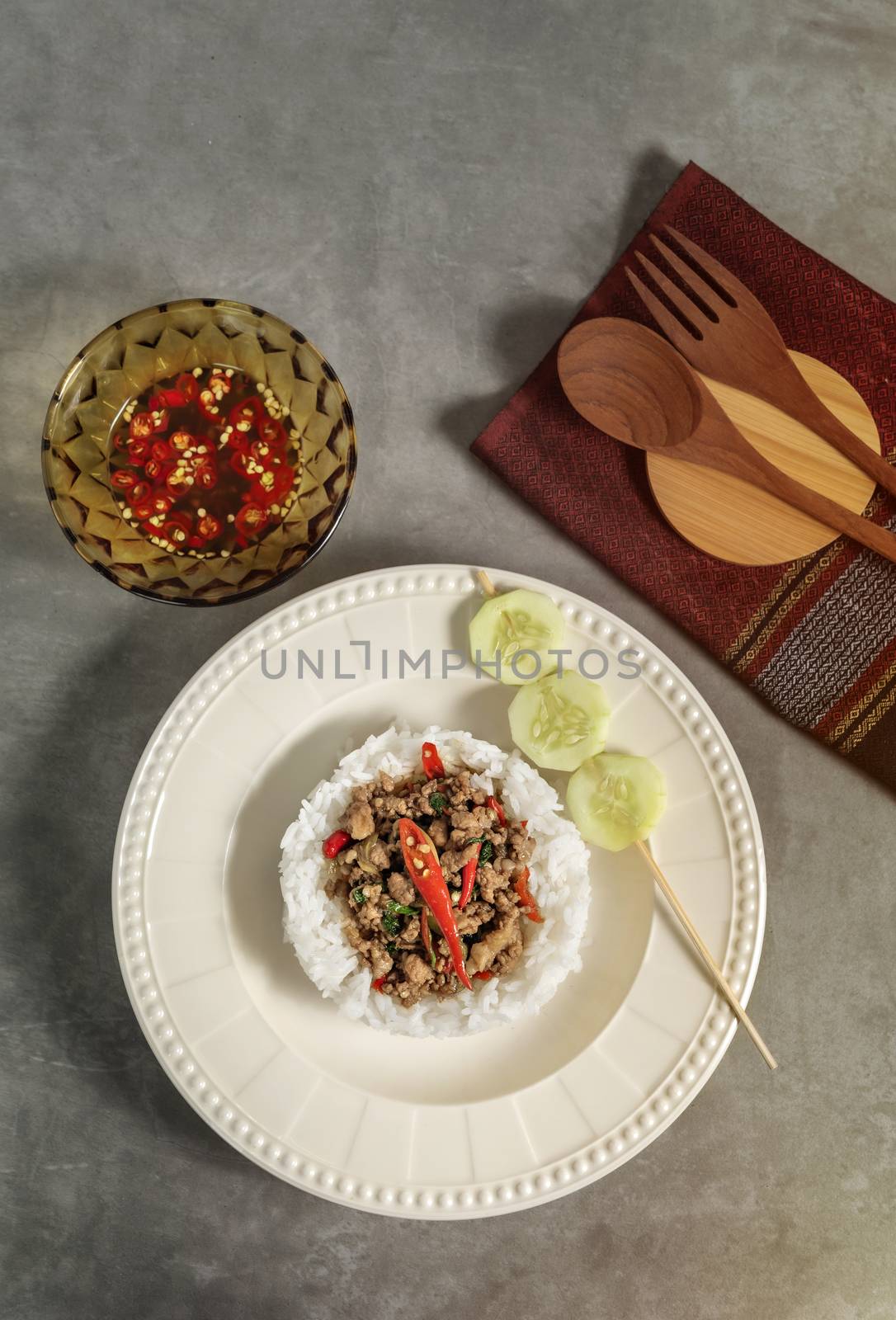 top view of steamed rice and minced pork fried with chilli pepper and sweet basil served with fresh cucumber and spicy sauce