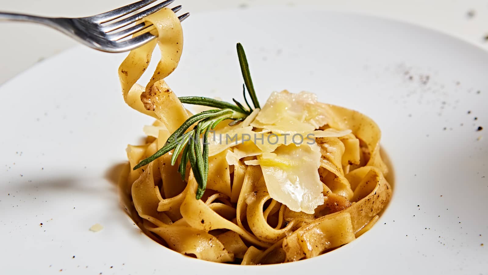 Close-up italian pasta plate with grated parmesan cheese and basil leaf.