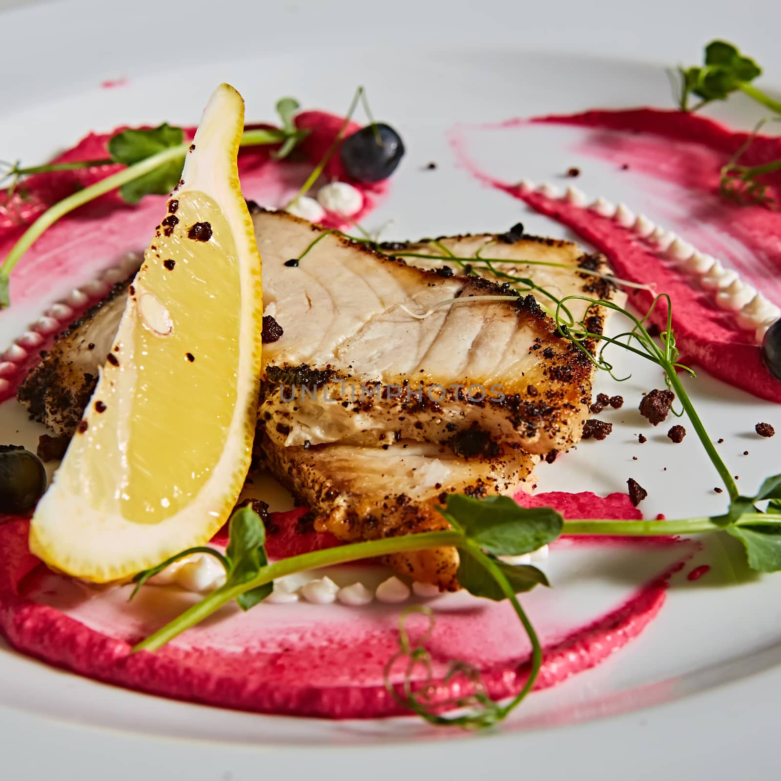 White fish with lemon on white plate, selective focus.